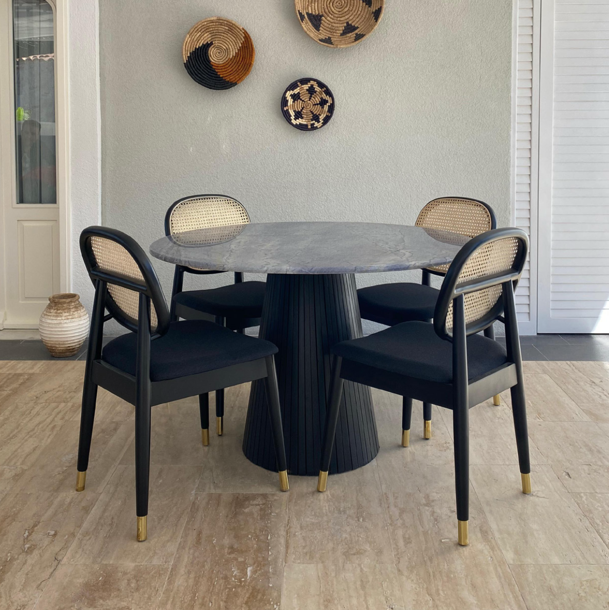 Modern round marble dining table paired with NOMO black handmade chairs featuring cane backrests and gold-tipped legs, by Nuovo Kitchens Vancouver.