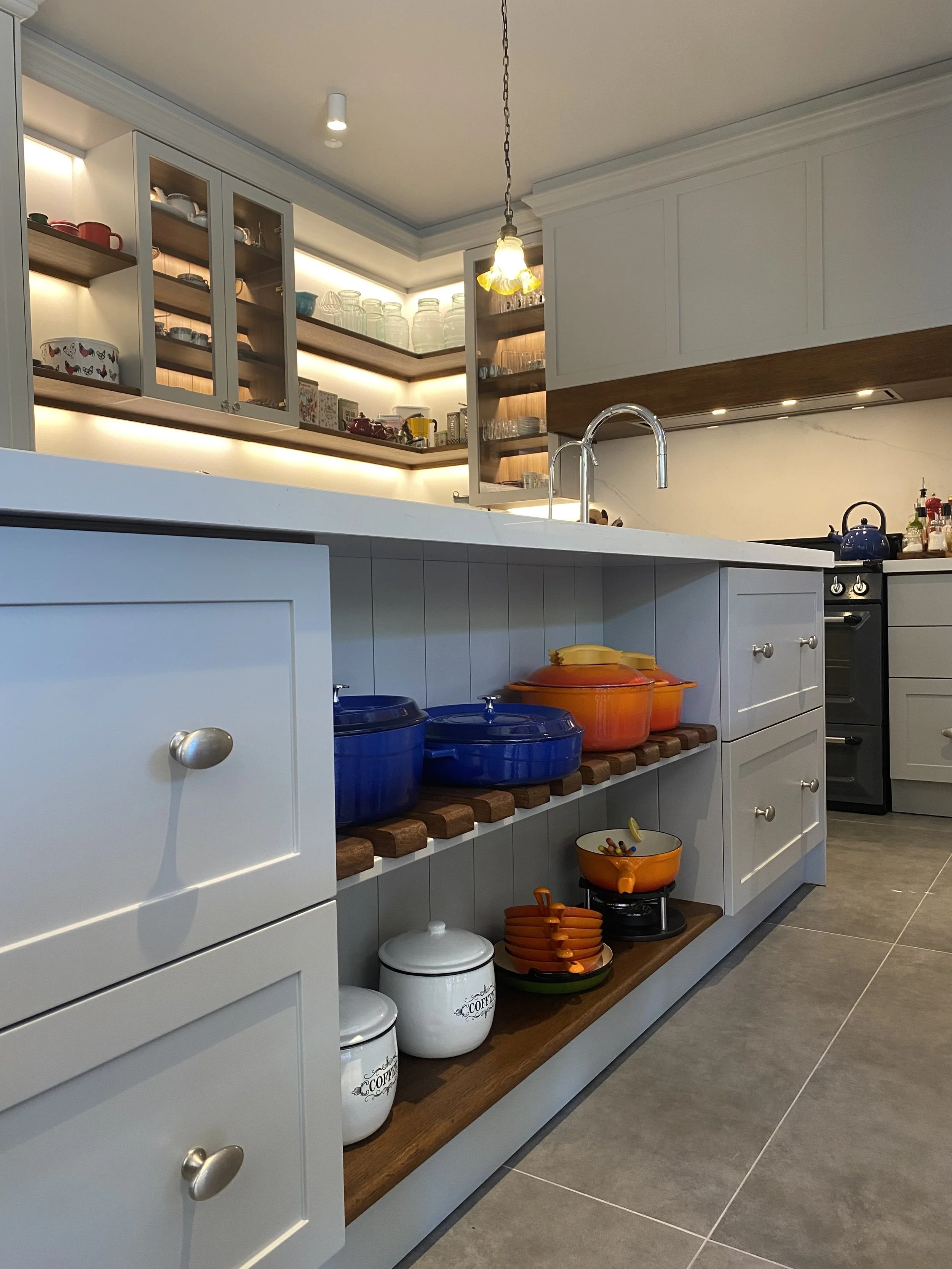 Eclectic modern kitchen featuring soft-grey lacquered HDF shaker cabinetry and marble-veined Cosentino quartz backsplash - cabinet lower shelves detail. 
