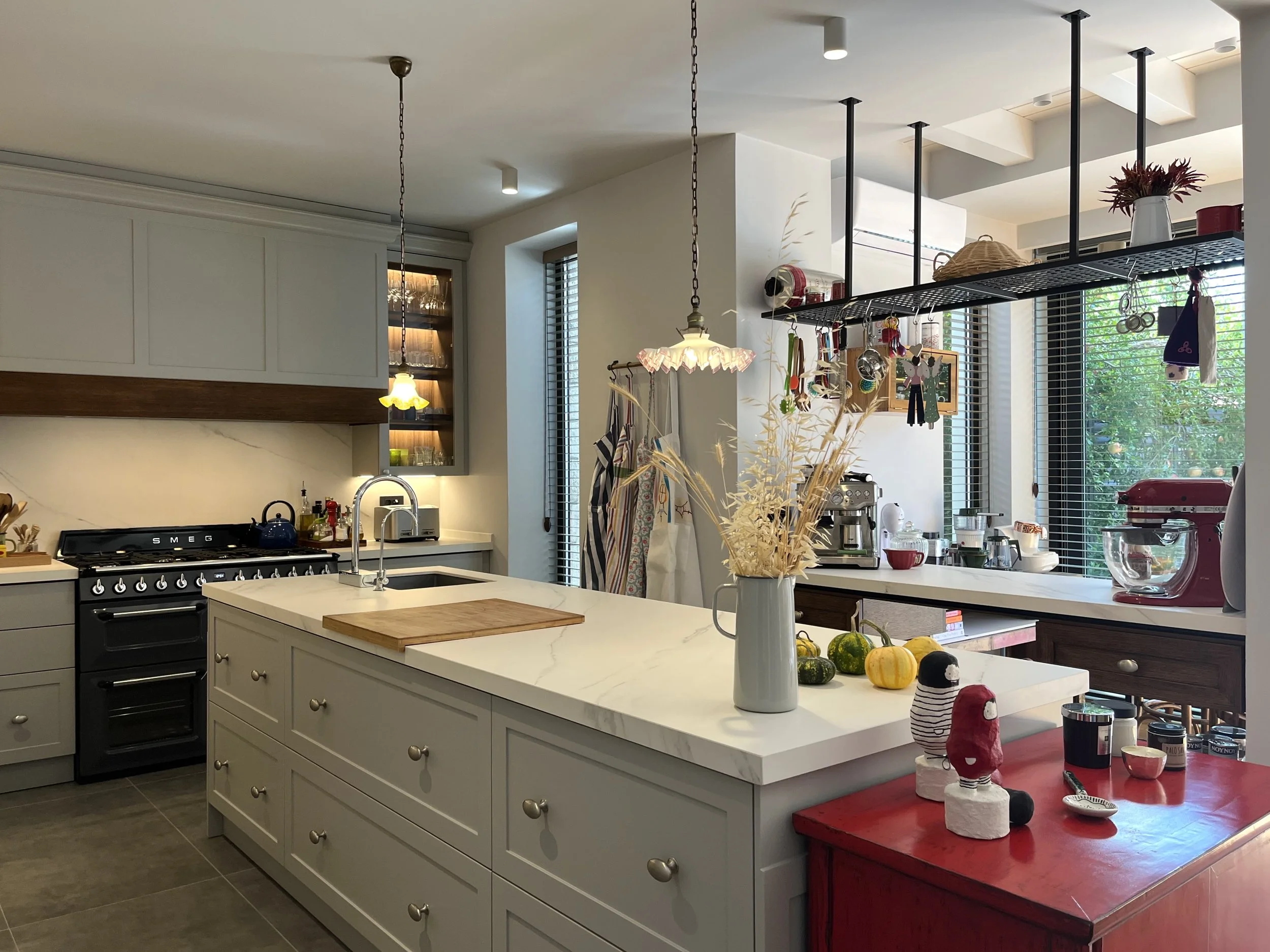 Eclectic modern kitchen featuring soft-grey lacquered HDF shaker cabinetry, warm wood accents, and a marble-veined Cosentino quartz backsplash, with integrated LED lighting. 