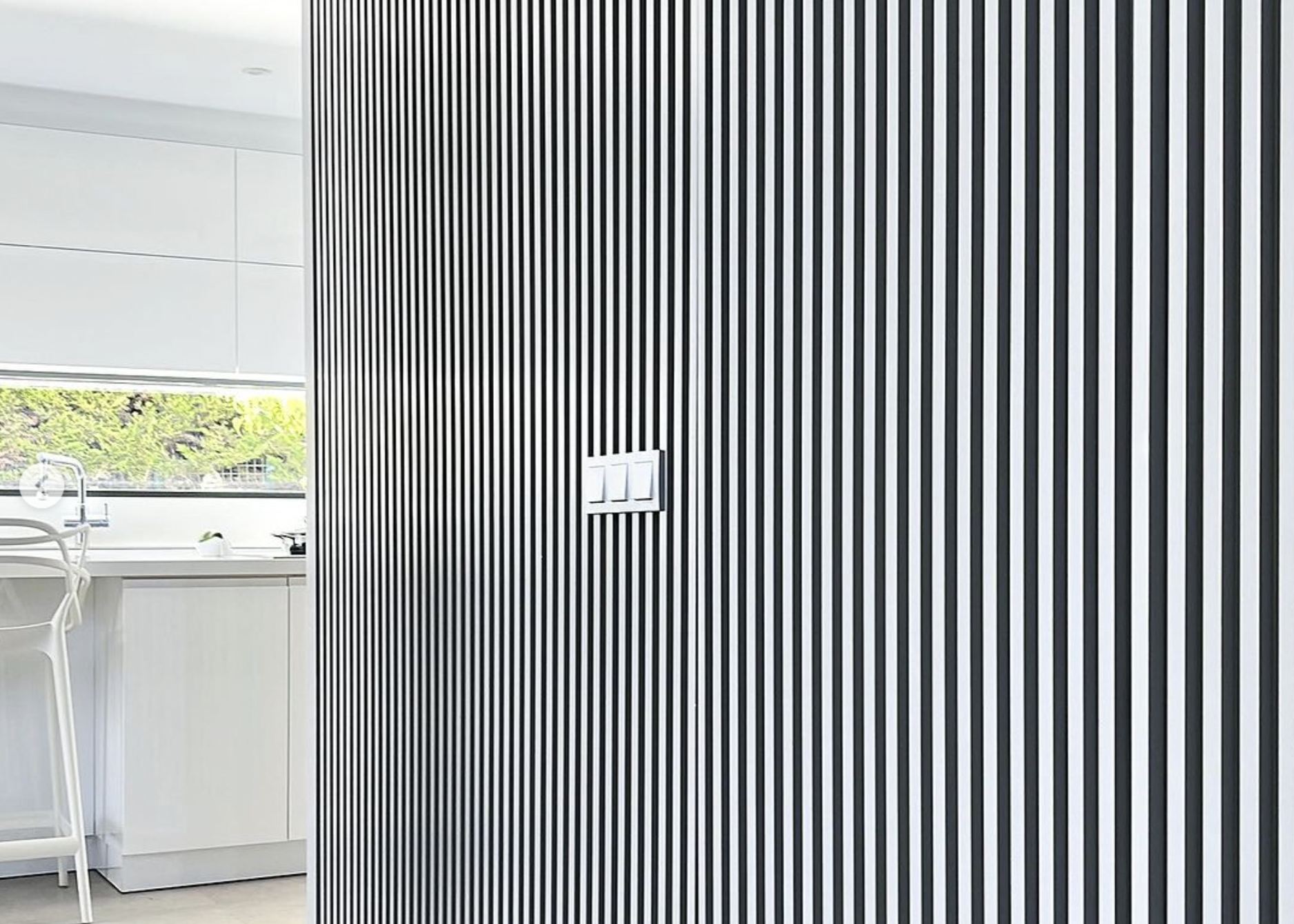 Ultra-modern fluted kitchen with custom vertical slatted cabinet doors, integrated appliances and a bright white island, crafted by Nuovo Kitchens in Vancouver.