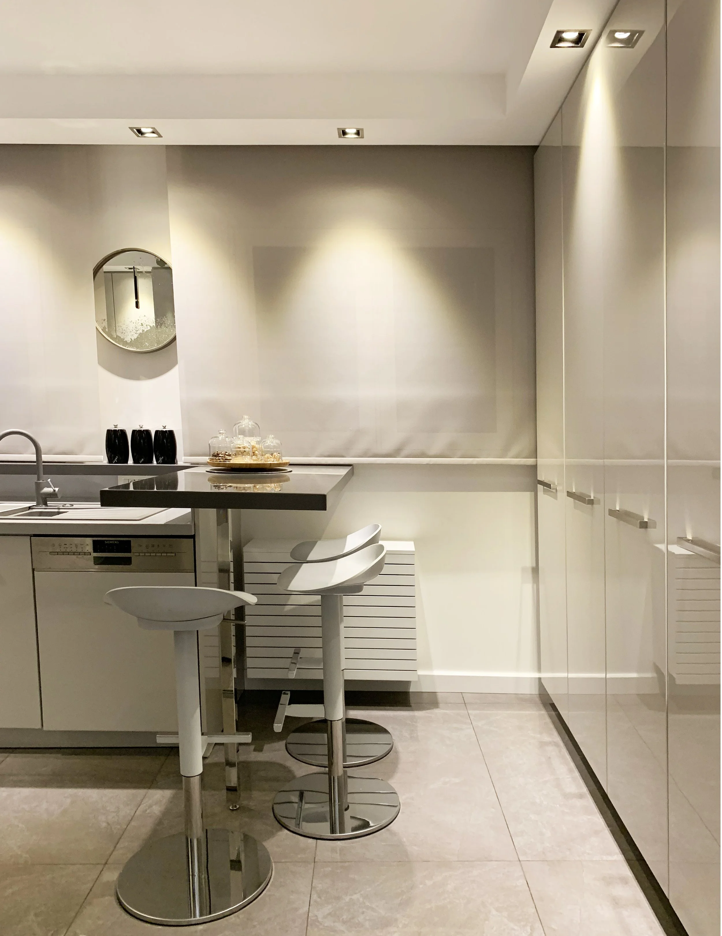 Compact modern kitchen in Vancouver featuring high-gloss white cabinets and an integrated dining counter, making the utmost use of the space. 
