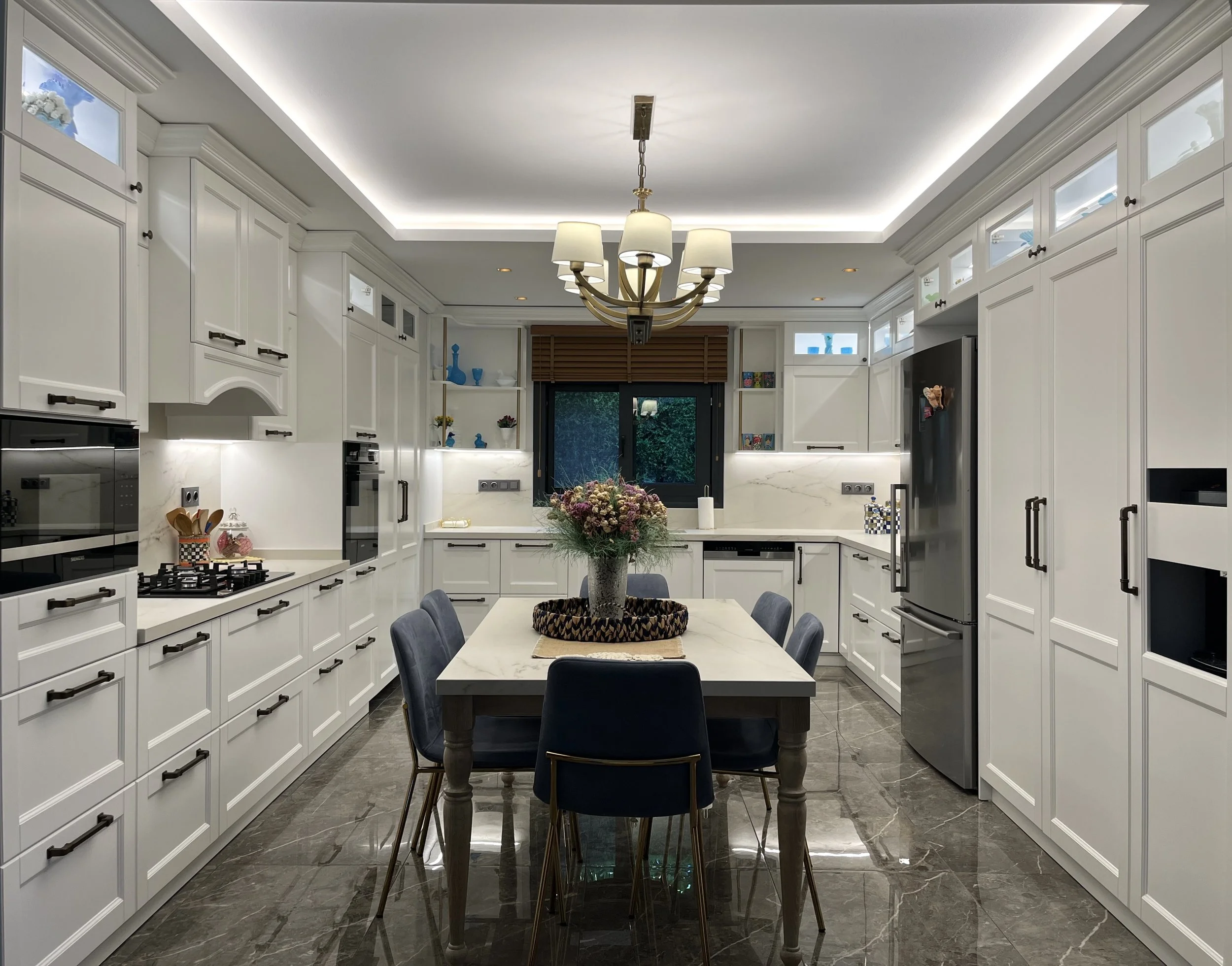 Luxury off-white kitchen design with integrated Cosentino quartz surfaces and traditional high-contrast black hardware.