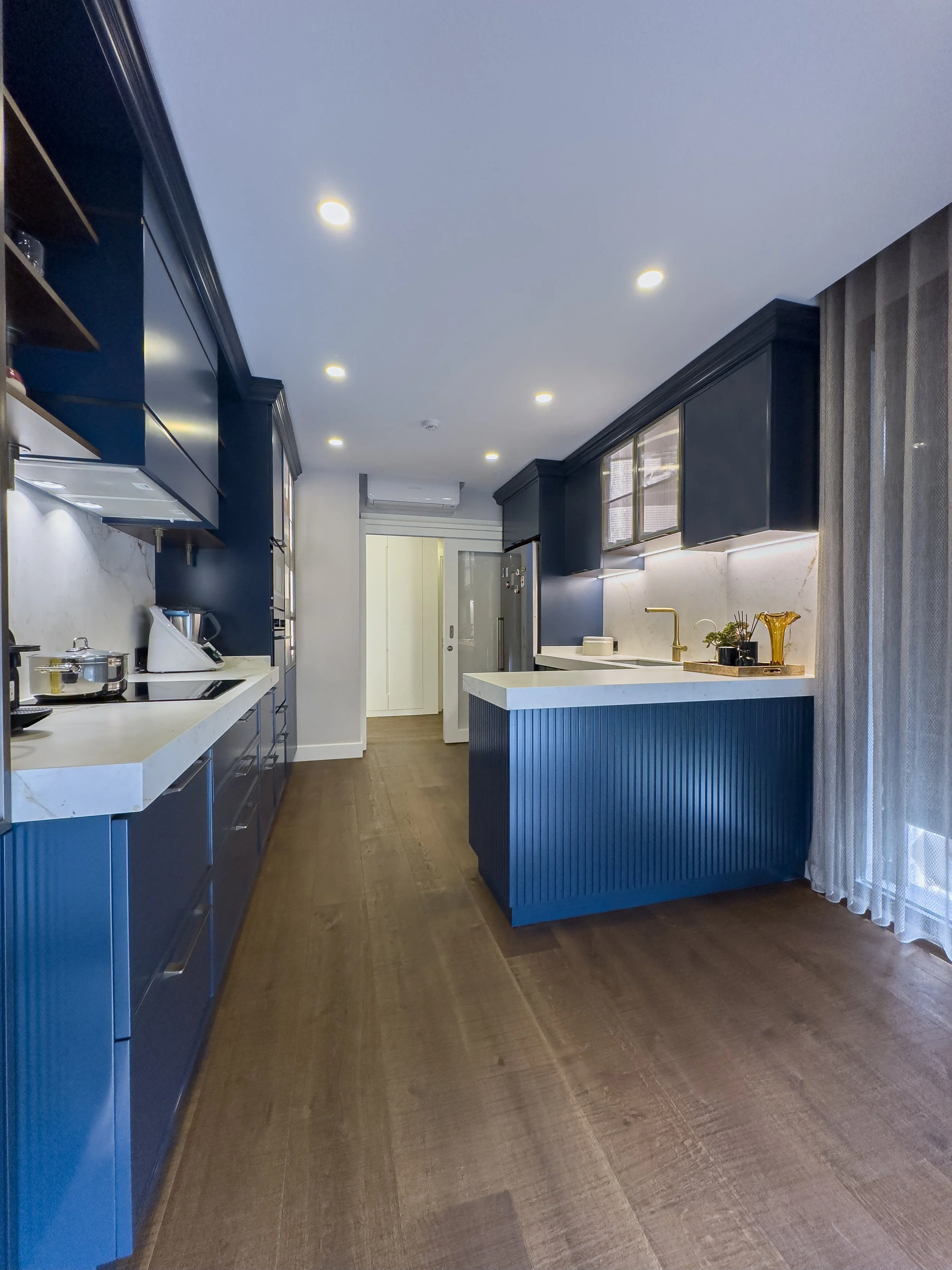 Marine-blue lacquer custom kitchen cabinets with fluted detailing, white quartz countertops and brass hardware – modern luxe kitchen by NUOVO Kitchens Vancouver.