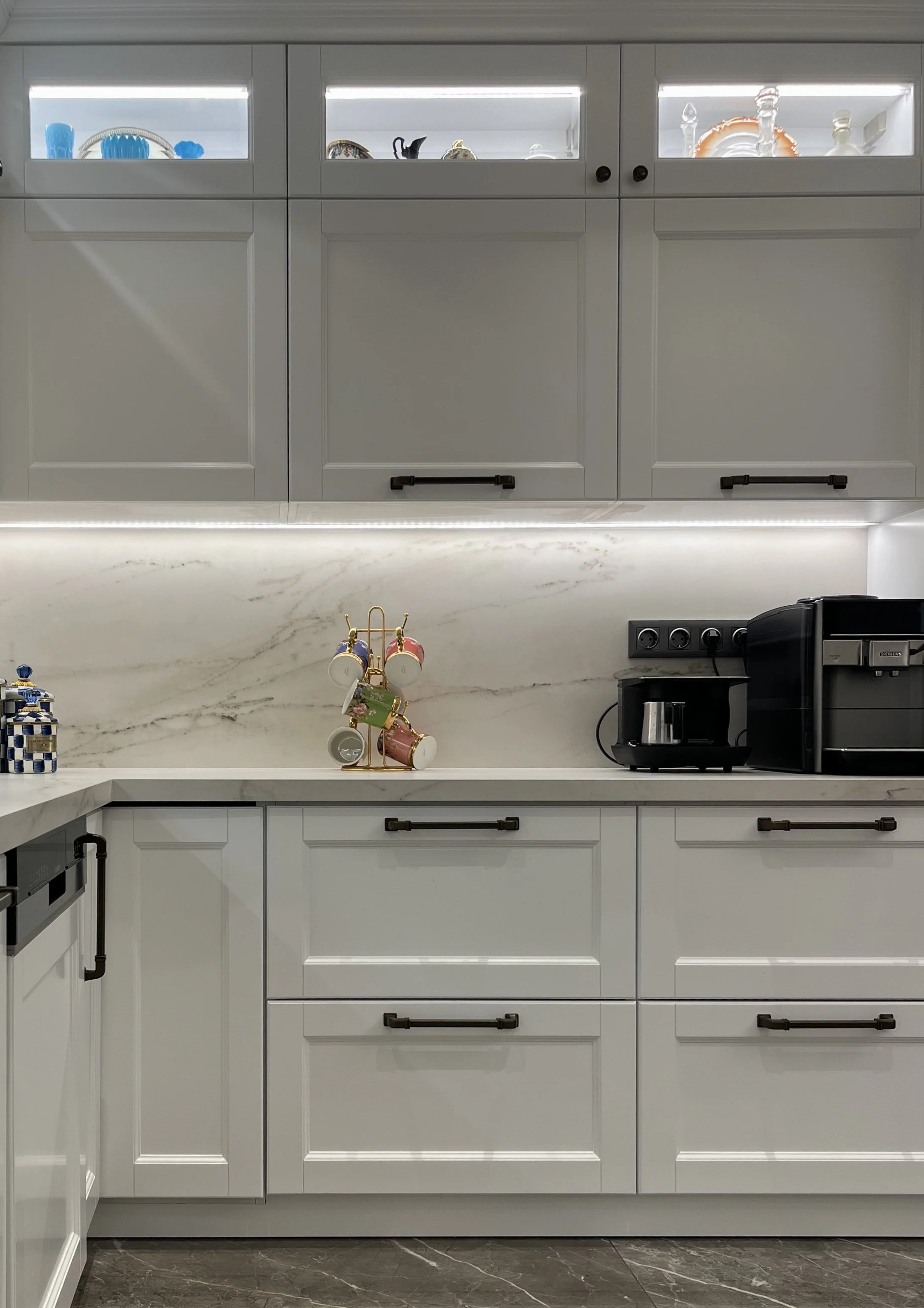 Luxury off-white kitchen design with integrated Cosentino quartz surfaces and traditional high-contrast black hardware.