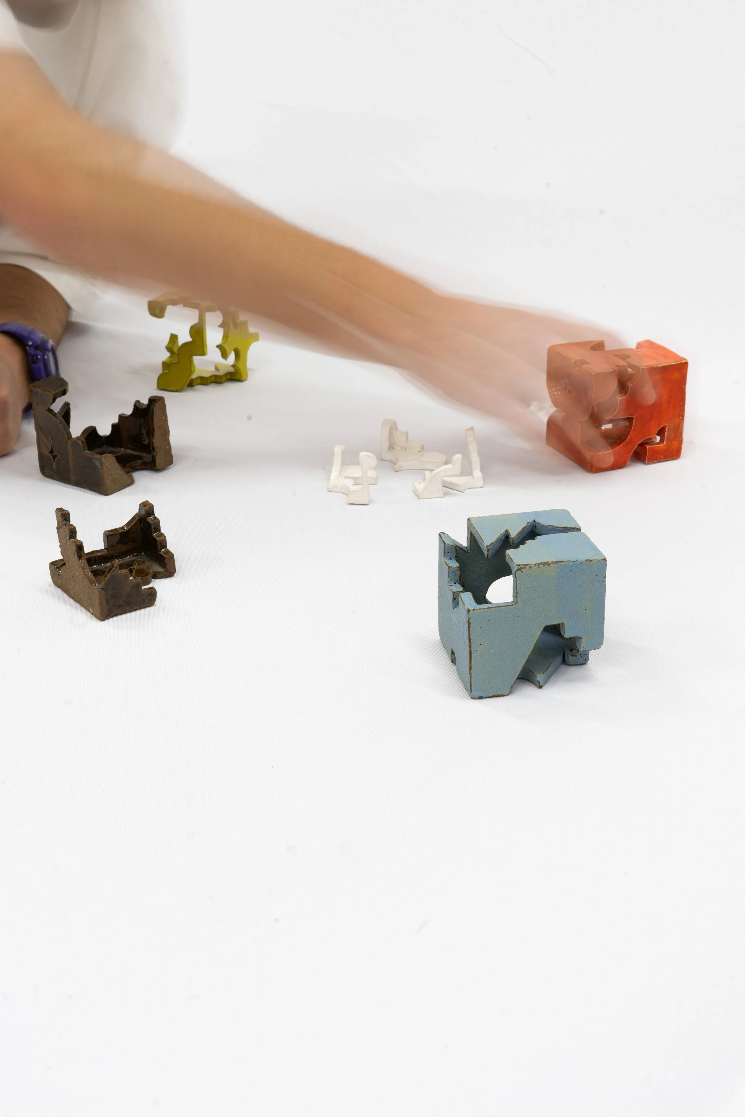 Various small colorful puzzle pieces placed on a white surface.
