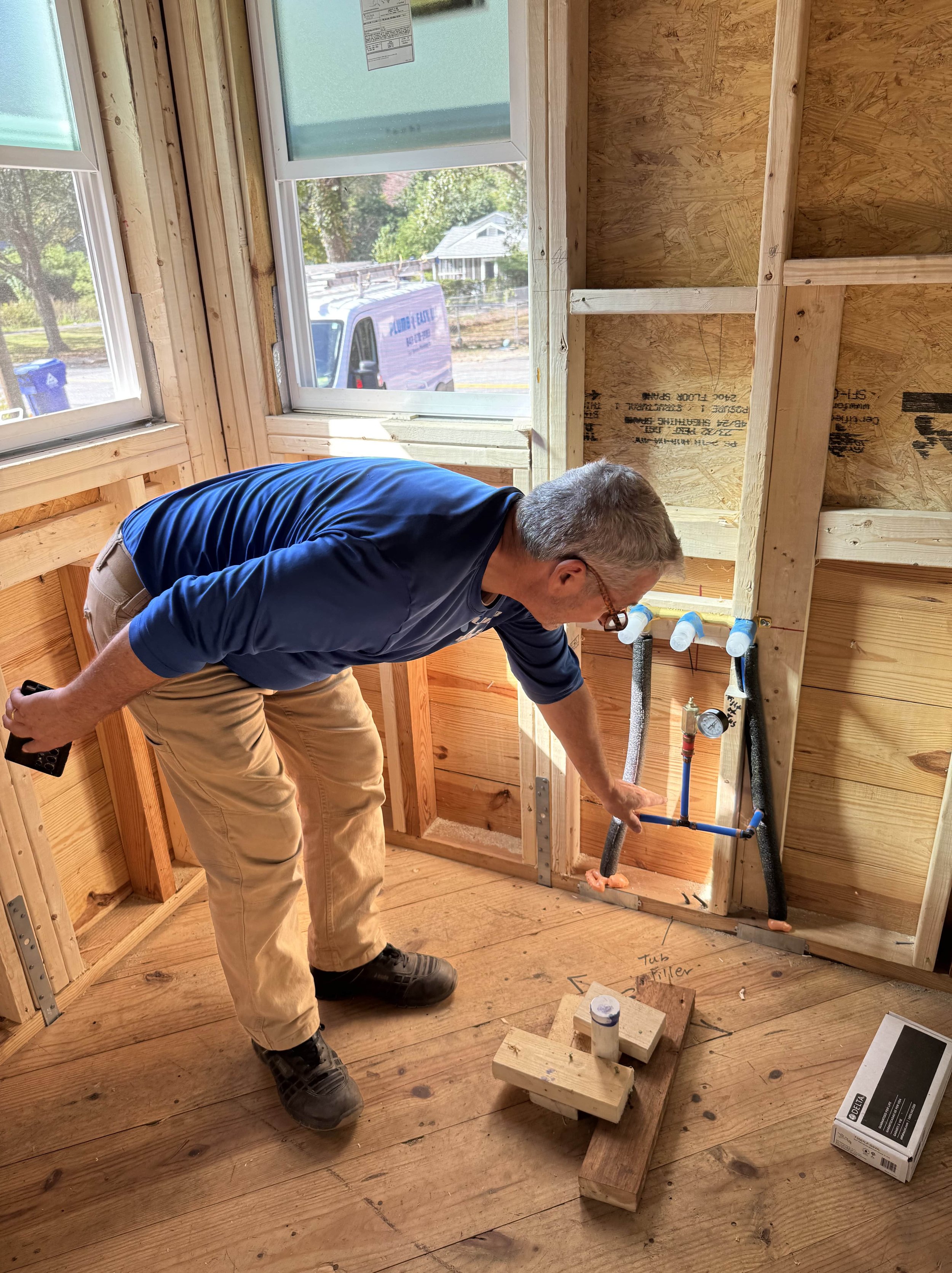 plumber in a house that's being built looking at the plumbing installation