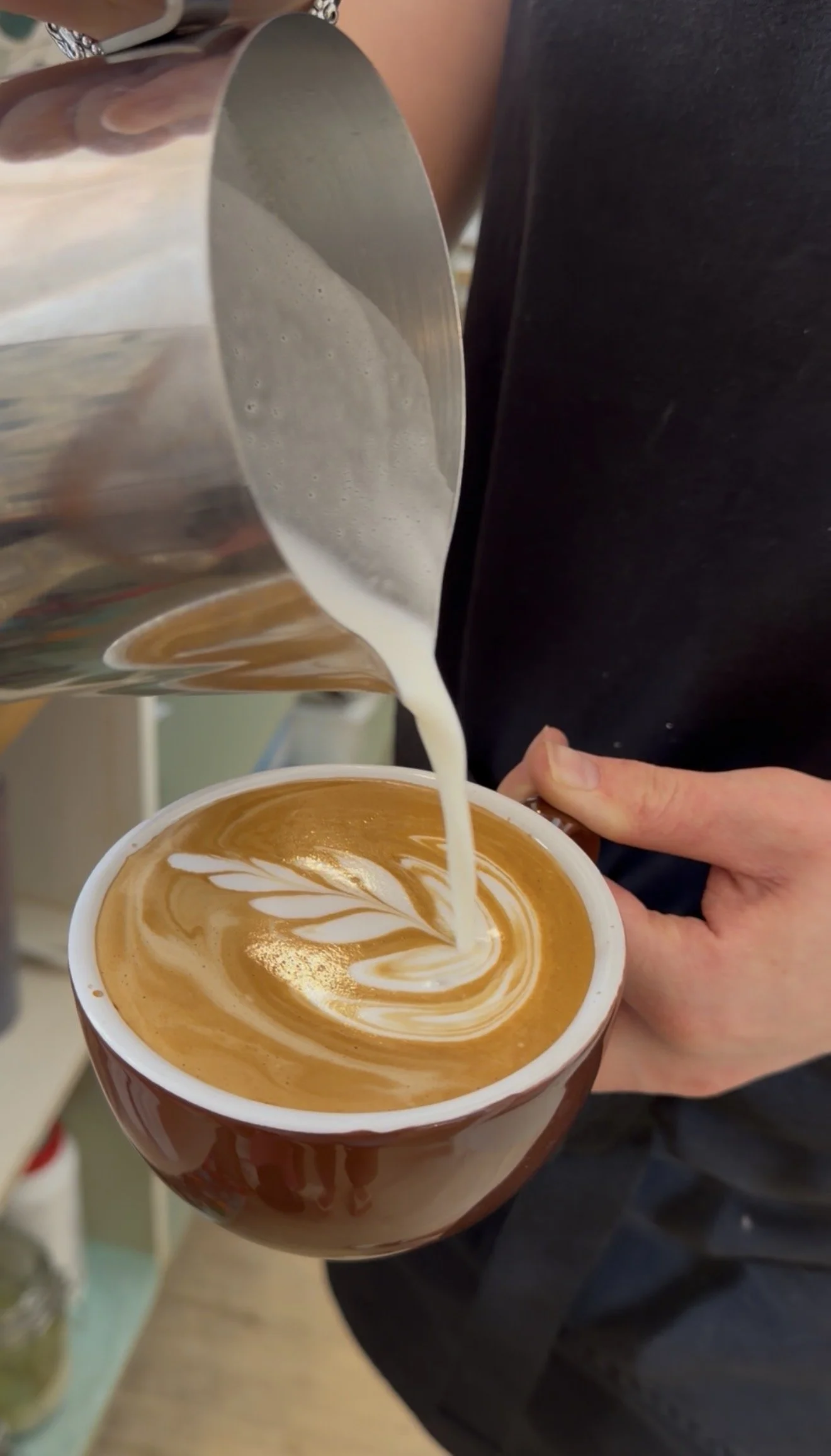 beautiful flat white coffee with latte art being poured by a skilled barista