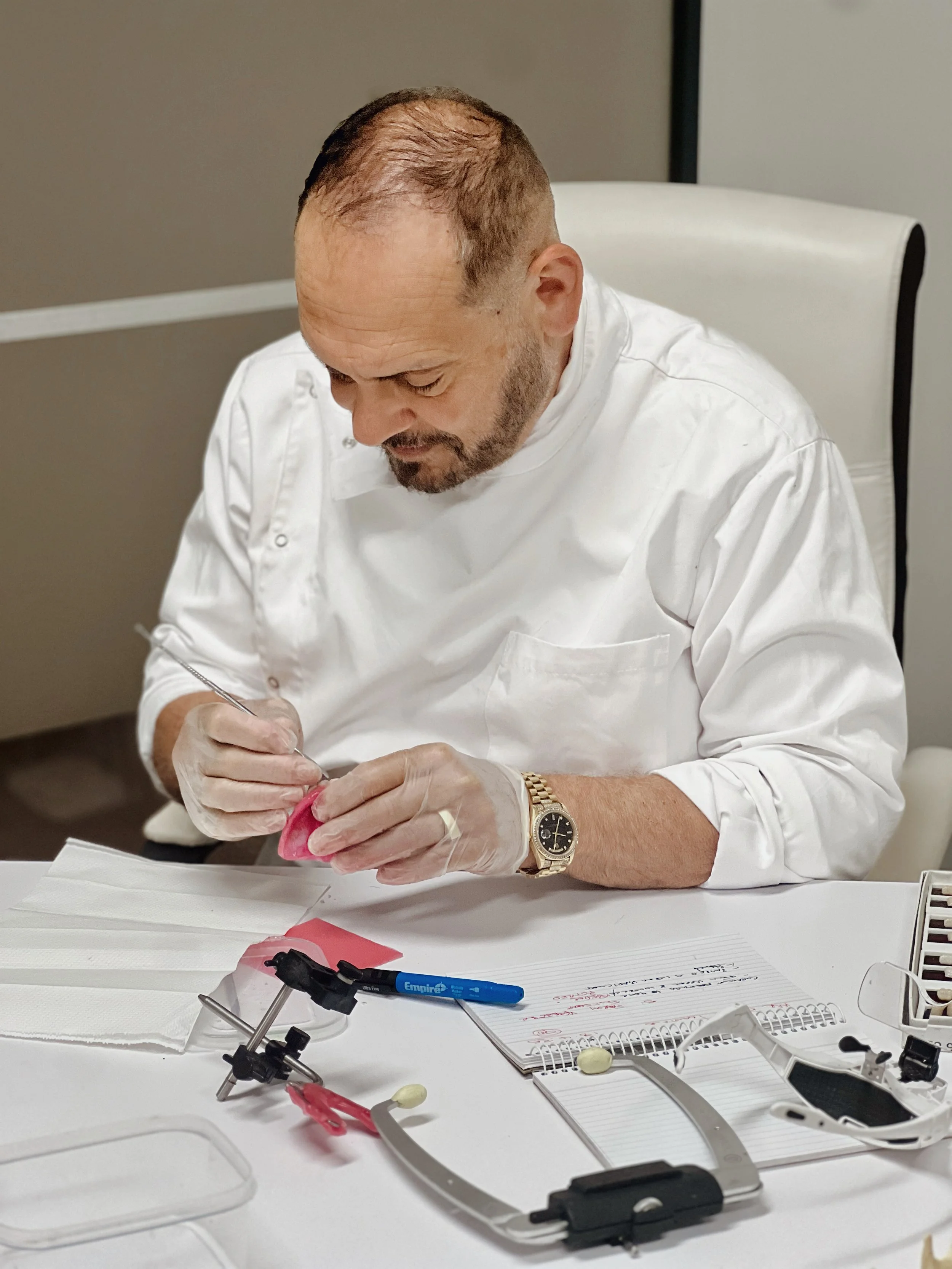It highlights the "hands-on" craftsmanship of Dr. Sebastian Riggio, an authority in Melbourne dental prosthetics with over 35 years of experience