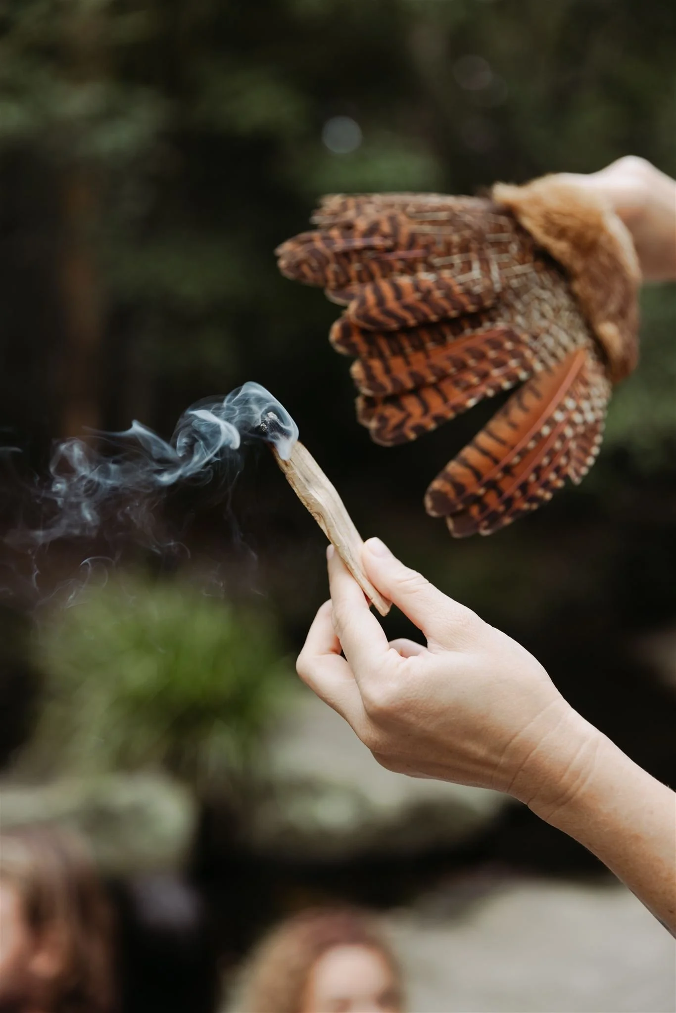 A feather wands wafting palo santo smoke to cleanse and clear