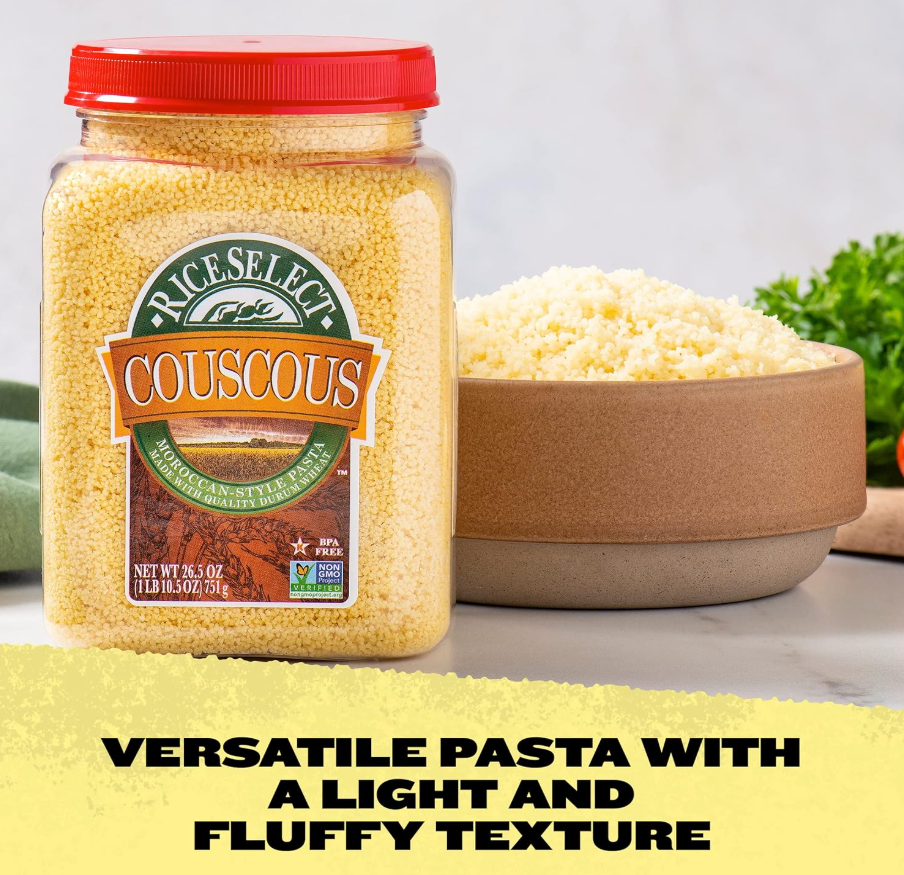 A jar of couscous next to a bowl filled with couscous, with some green herbs in the background.