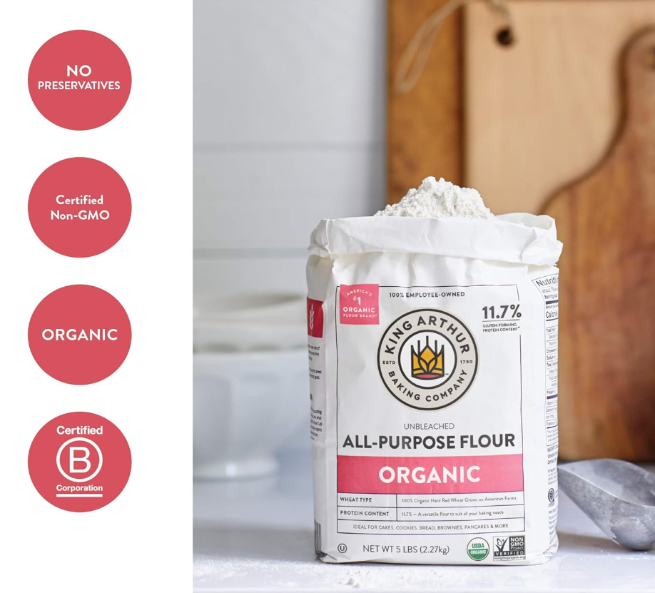 A 5-pound bag of King Arthur organic all-purpose flour on a kitchen countertop with a silver spoon nearby.