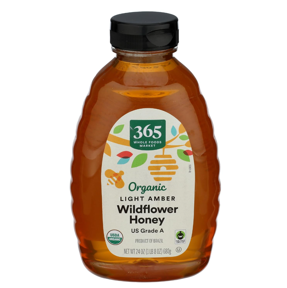 A jar of light amber wildflower honey from 365 Whole Foods Market, labeled as organic and USDA organic, with a black cap, produced in Brazil, weighing 24 ounces.