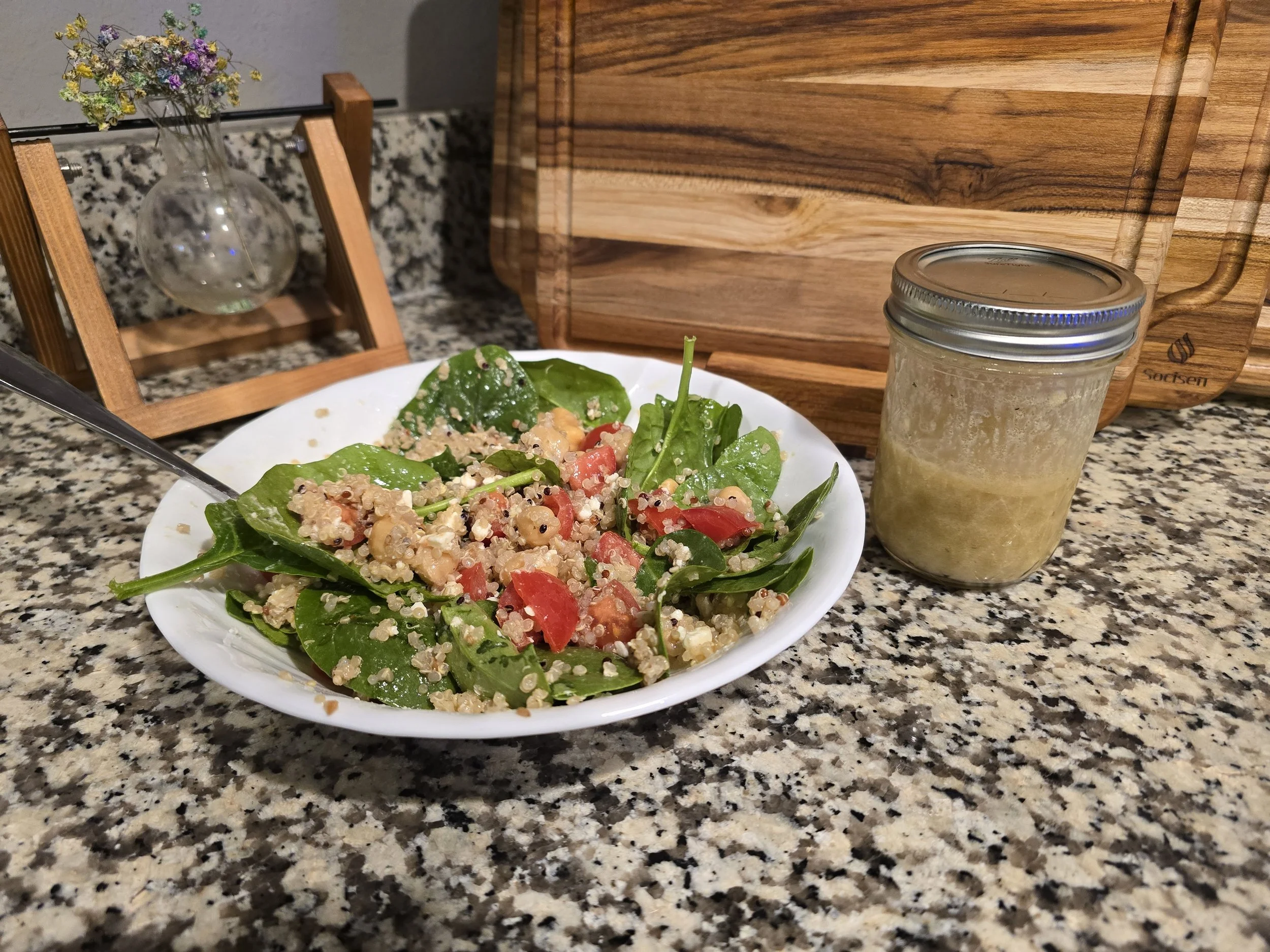 Chickpea and quinoa spinach salad with tomatoes and Dijon vinaigrette. Dressing stored in a Ball (Mason) Jar.