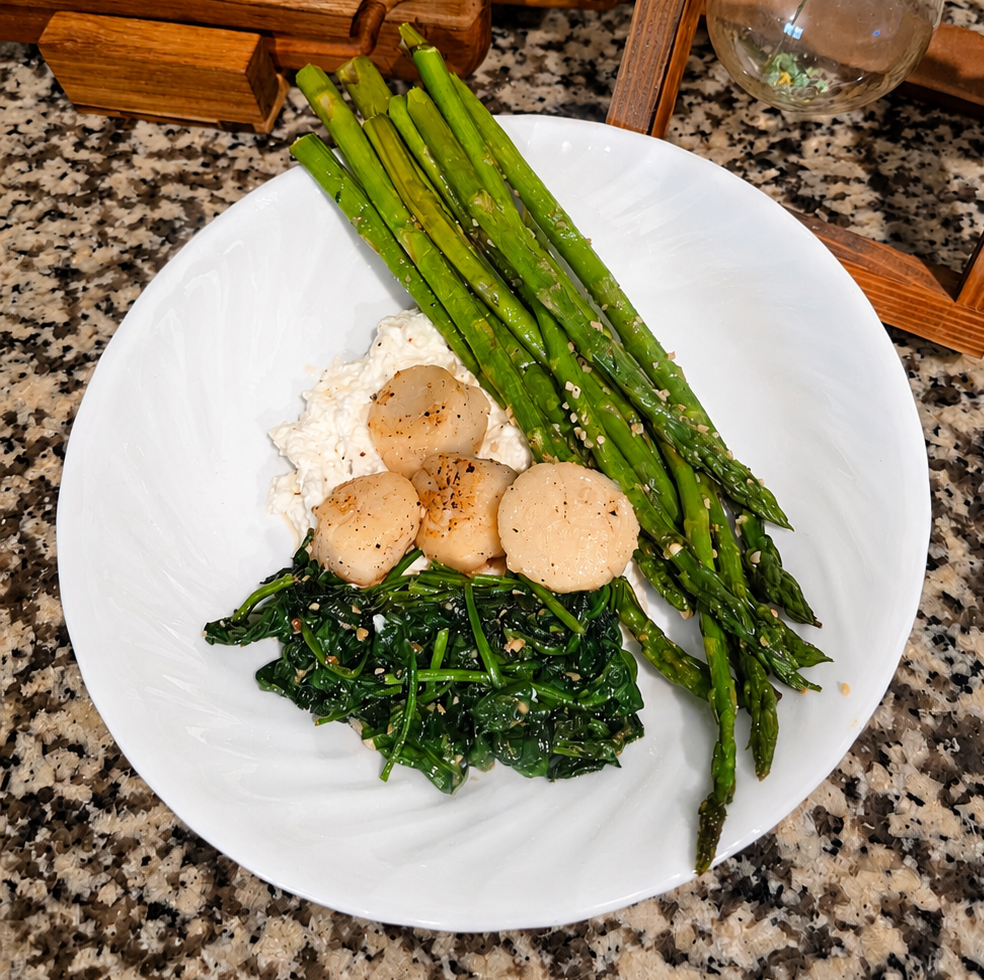 garlic butter scallops served with roasted asparagus, wilted spinach, and lemon ricotta