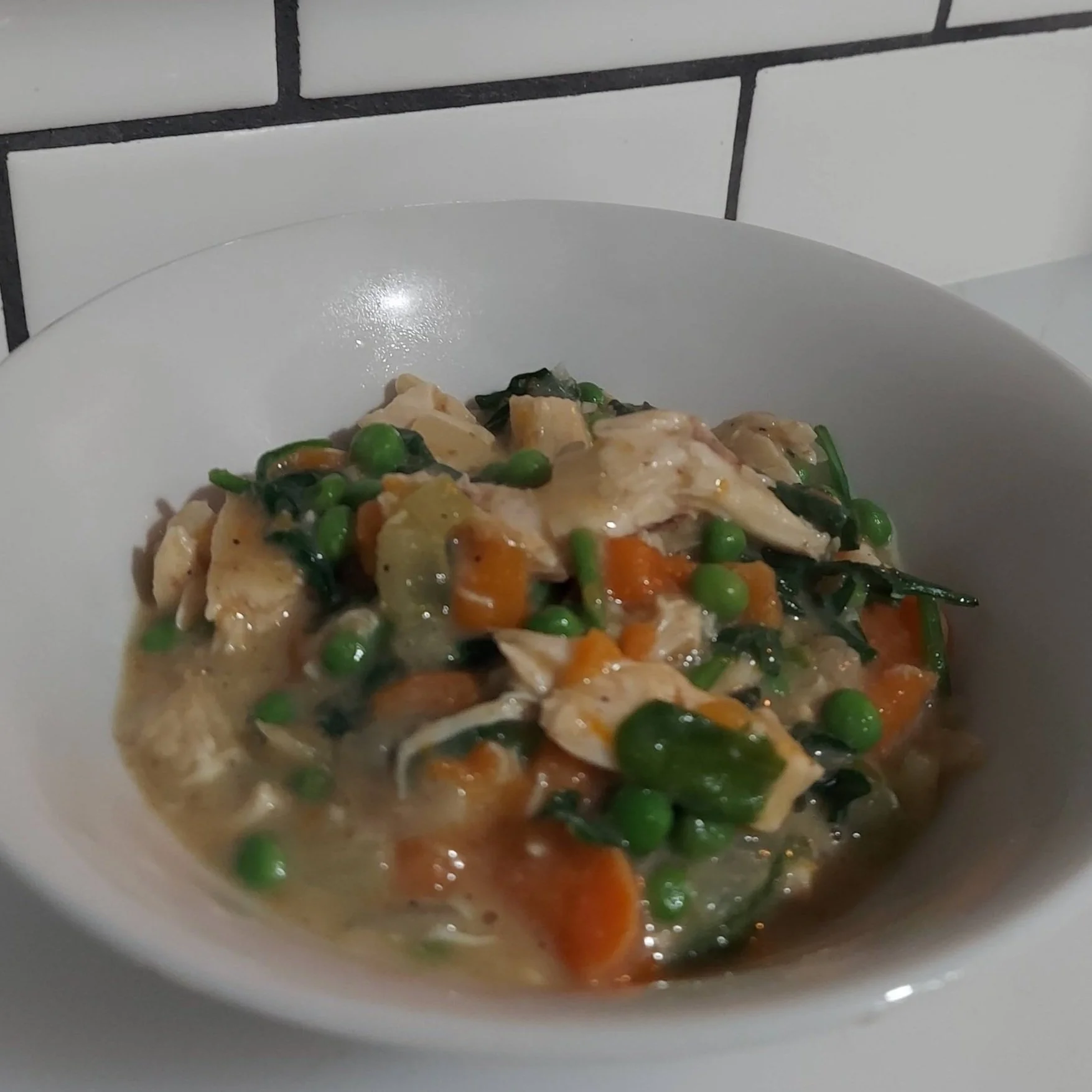 Bowl of creamy crustless turkey pot pie with chicken, peas, carrots, and spinach