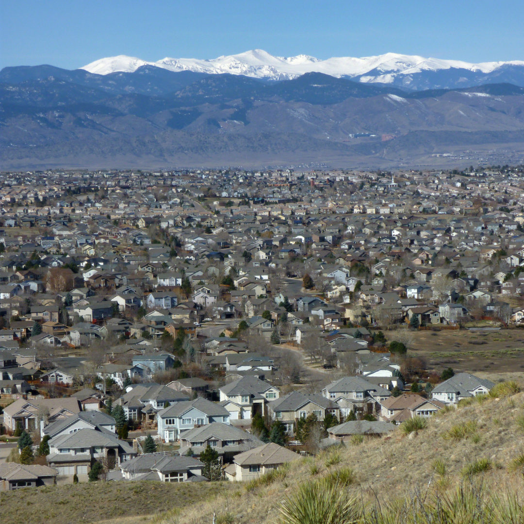 view of castle pines in the winter with mountains with snow. capped peaks in the back.