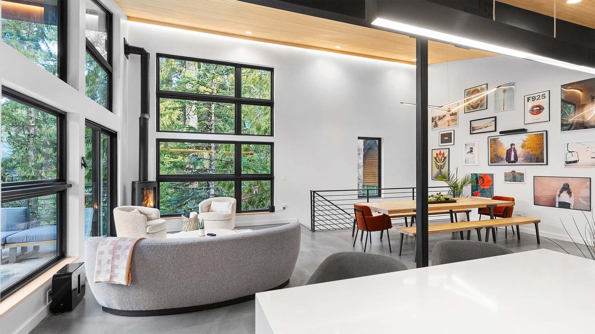 RAVN HAUS vacation rental Canopy level with curved sofa, dining table, gallery wall, and Mt. Hood forest views, Oregon.