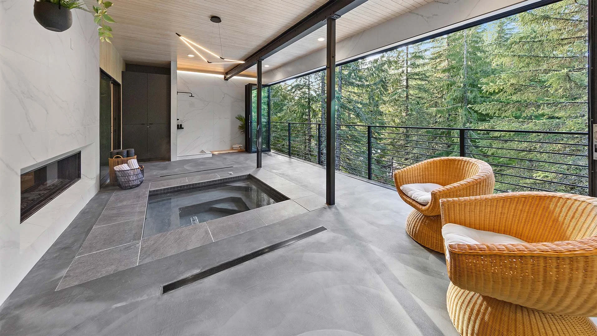 RAVN HAUS Understory spa with indoor hot tub, open glass walls, wicker chairs, and Mt. Hood forest views, Oregon.