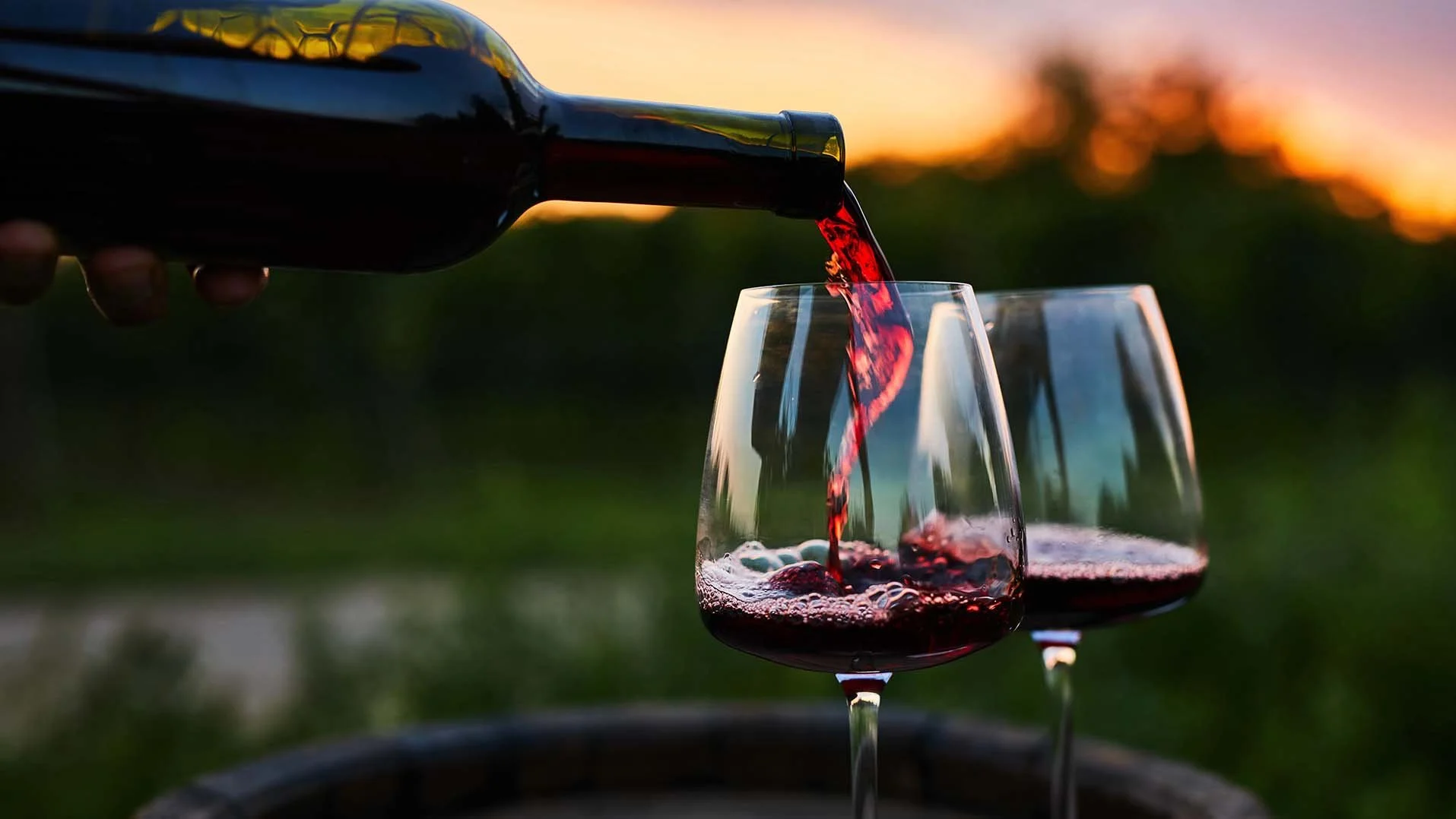 Red wine being poured into glasses at sunset during a Mt. Hood wine tour near RAVN HAUS modern alpine vacation rental in Government Camp, Oregon.