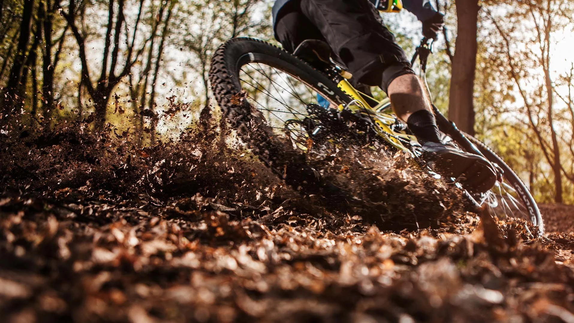 Mountain biker carving through dirt and leaves on a forest trail near Mt. Hood, kicking up debris during a high-speed turn close to RAVN HAUS modern alpine vacation rental in Government Camp, Oregon.