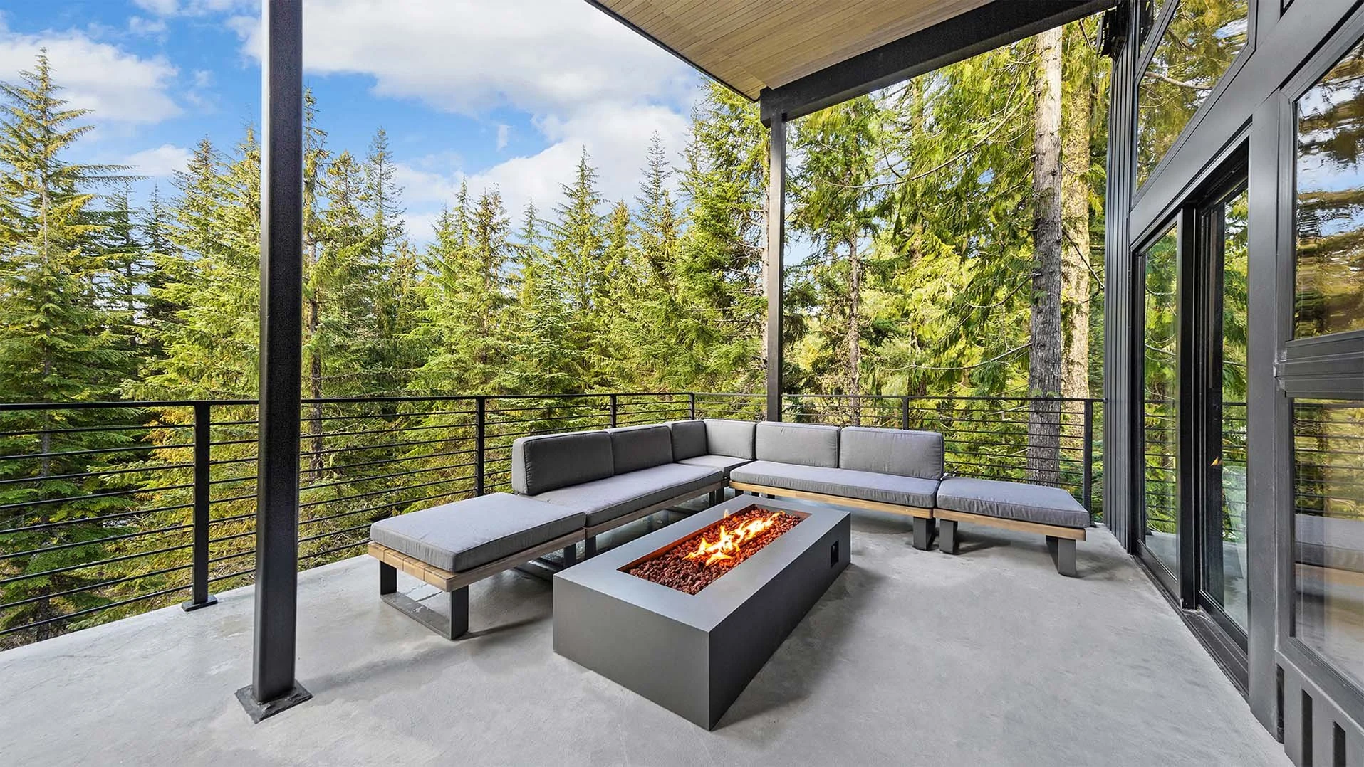 Cozy treetop seating area on the Canopy deck at RAVN HAUS Mt. Hood vacation rental featuring a contemporary fire pit and outdoor chairs.