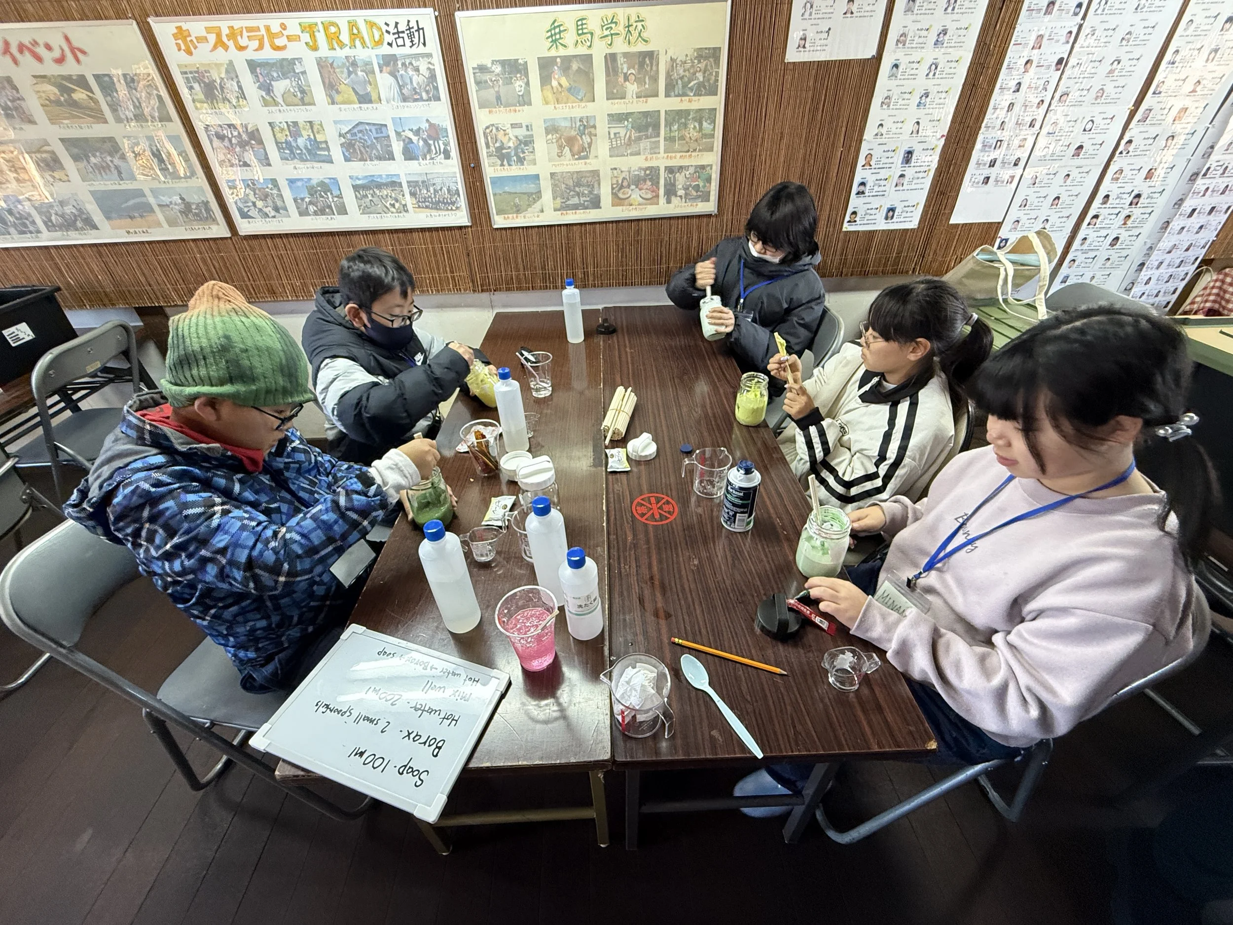 屋内のテーブルで子供たちがアイスクリームを食べている。背景には掲示板や写真が貼られている。