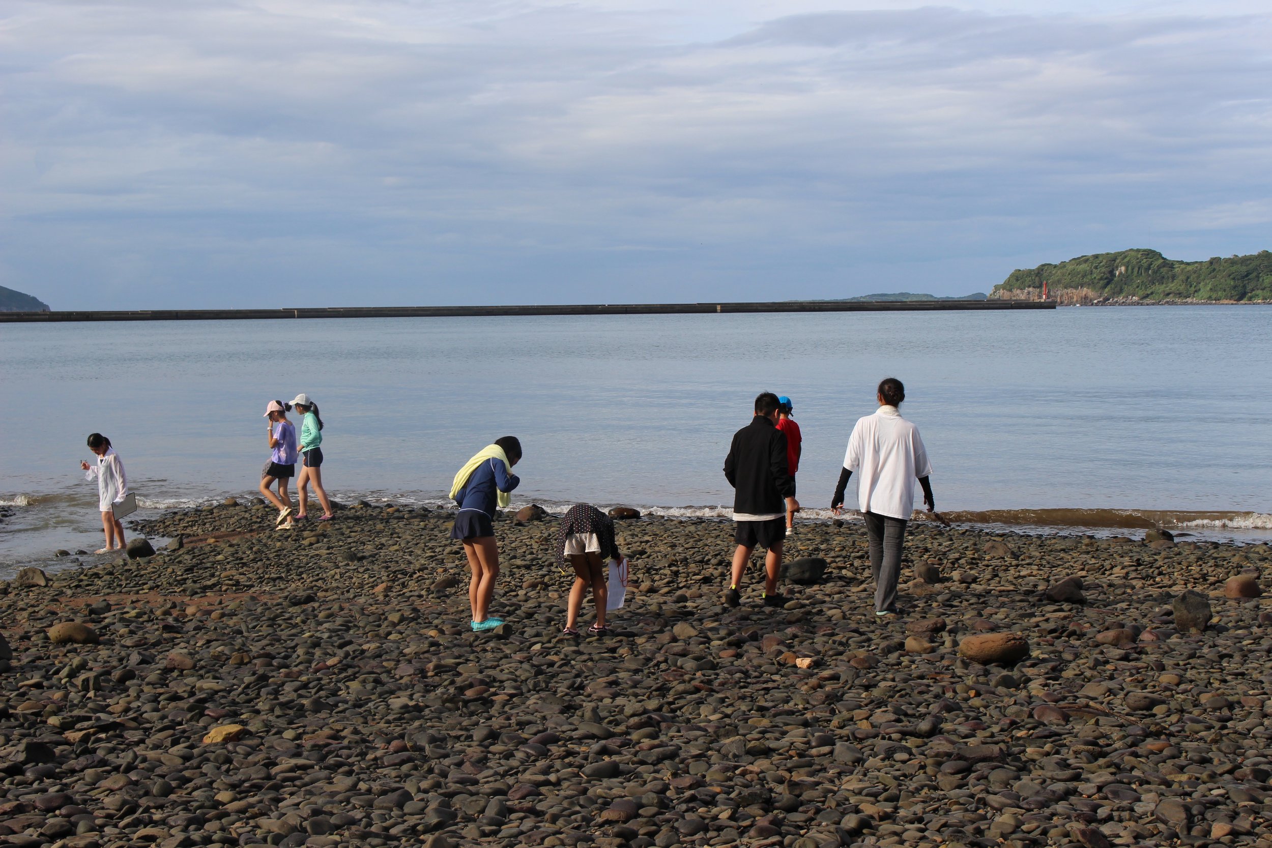 海辺の岩たちの上を歩く人々のグループ