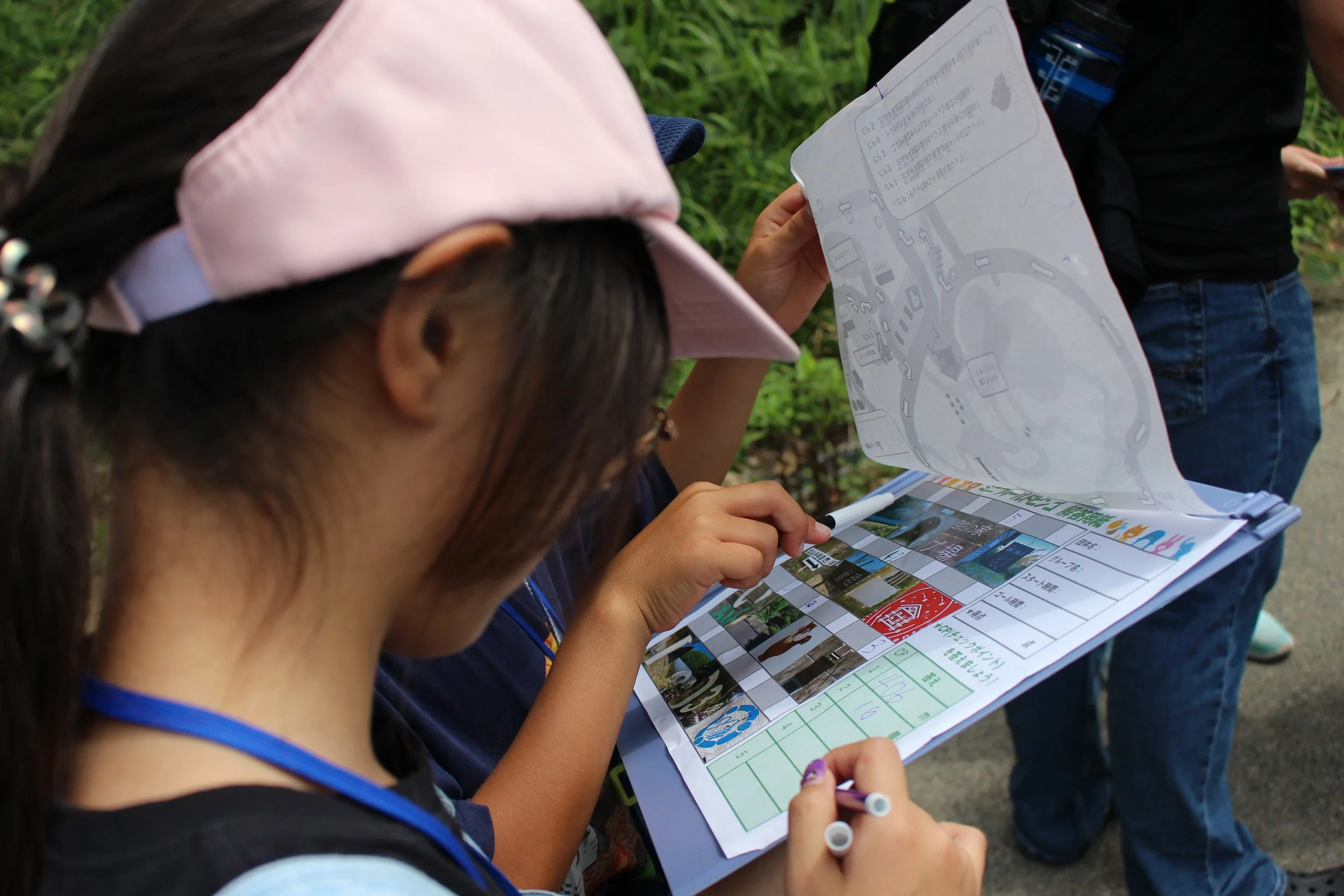 少女が地図と情報シートを見ながら記入している。