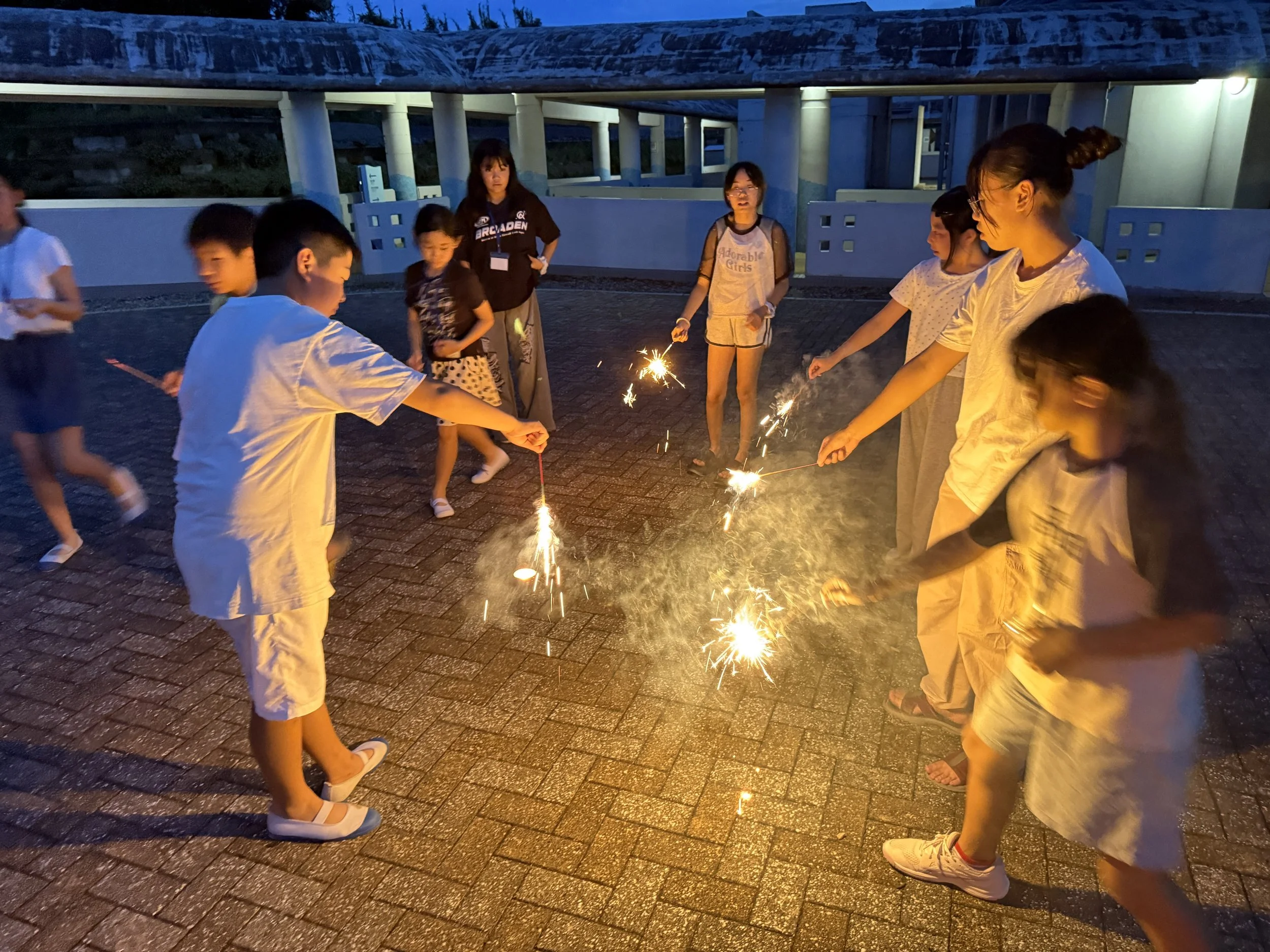 夜に屋外で花火や火花を楽しむ子供たち。子供たちが線香花火を持ち、その火花を楽しんでいる。