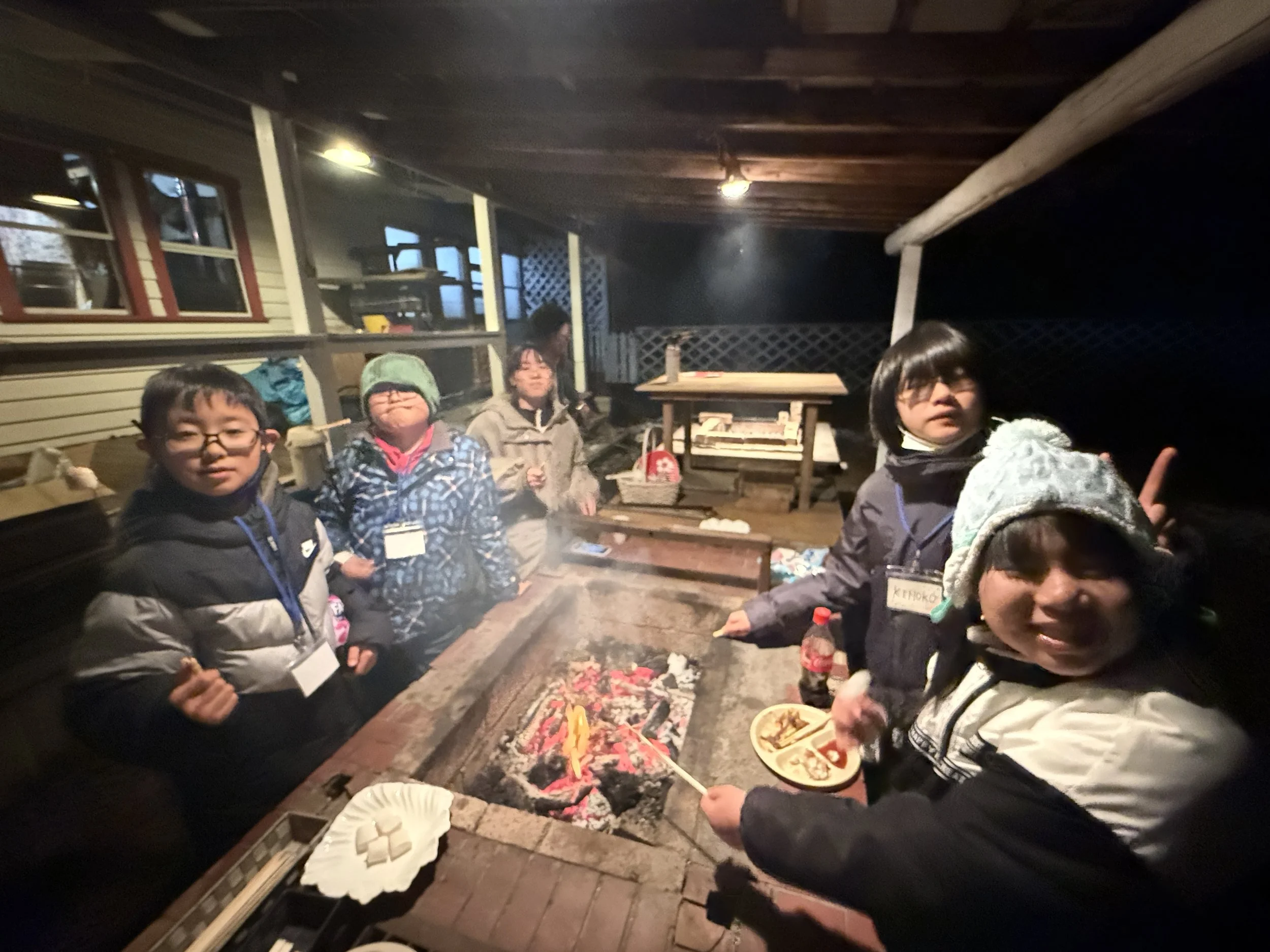 夜の屋外で子供たちが焚き火を囲んでいる写真