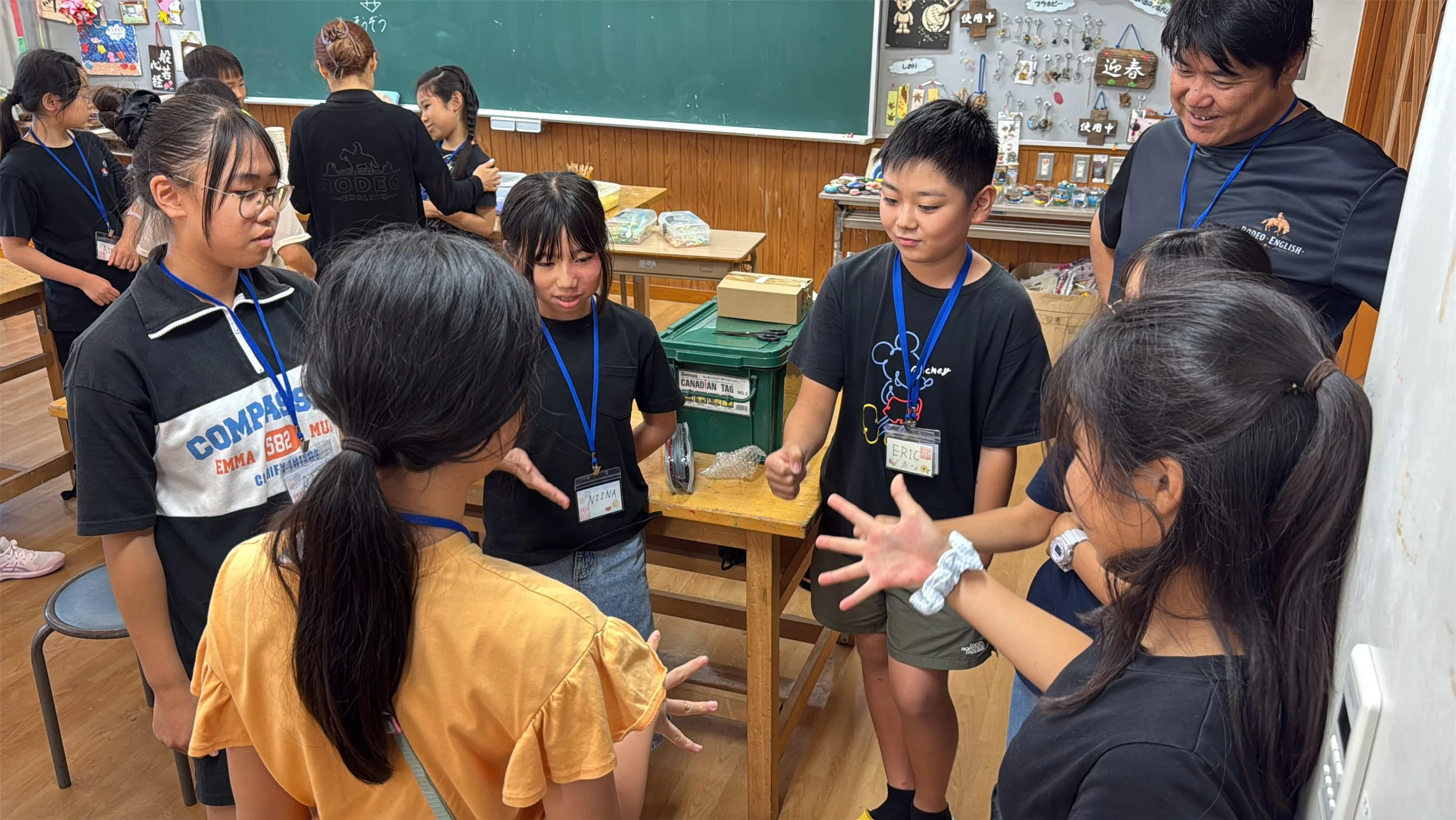 教室内で子供たちがゲームや活動をしている。教師も参加している。