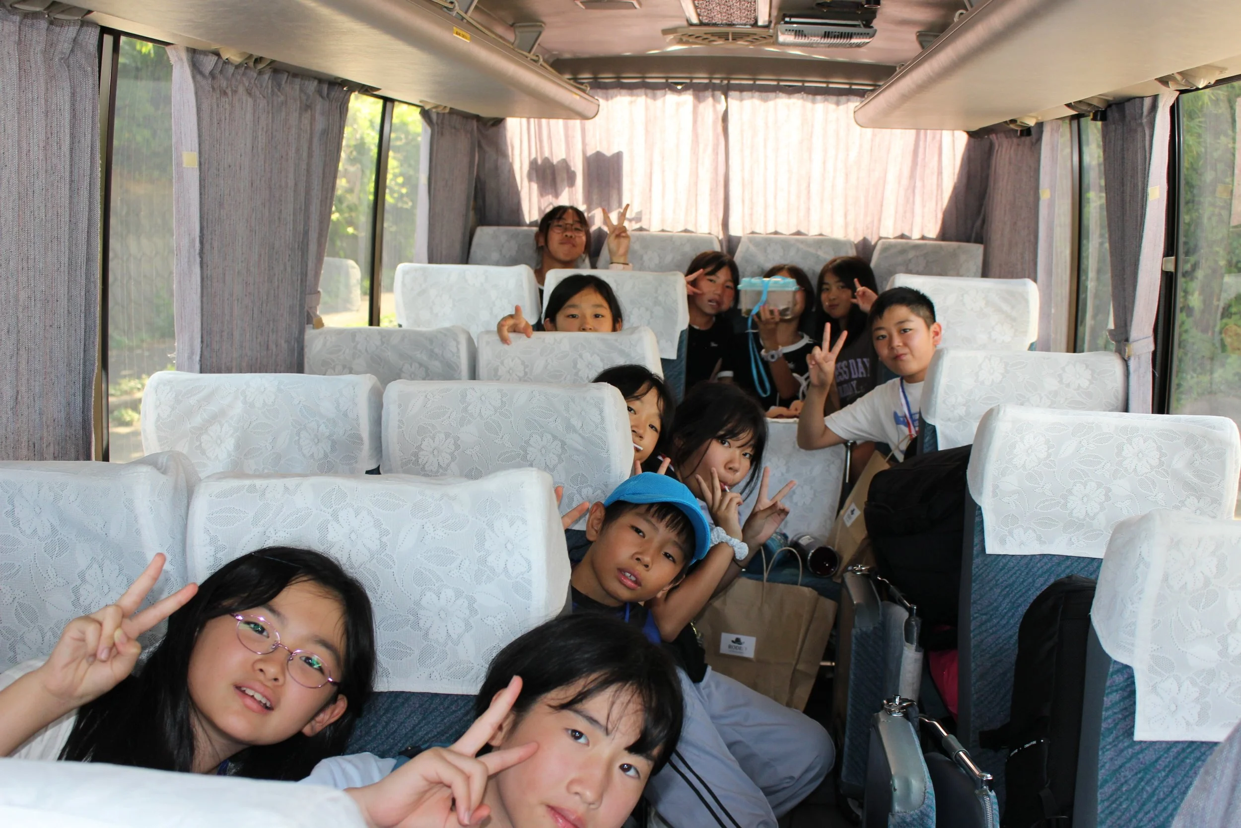 バスの座席に座る子供たちと大人たちのグループ。