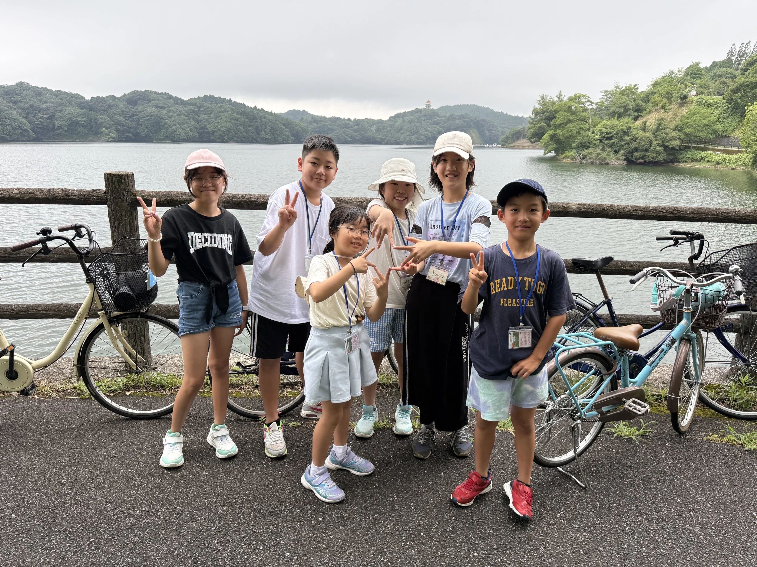 湖のそばで記念撮影をする子供たちのグループと自転車