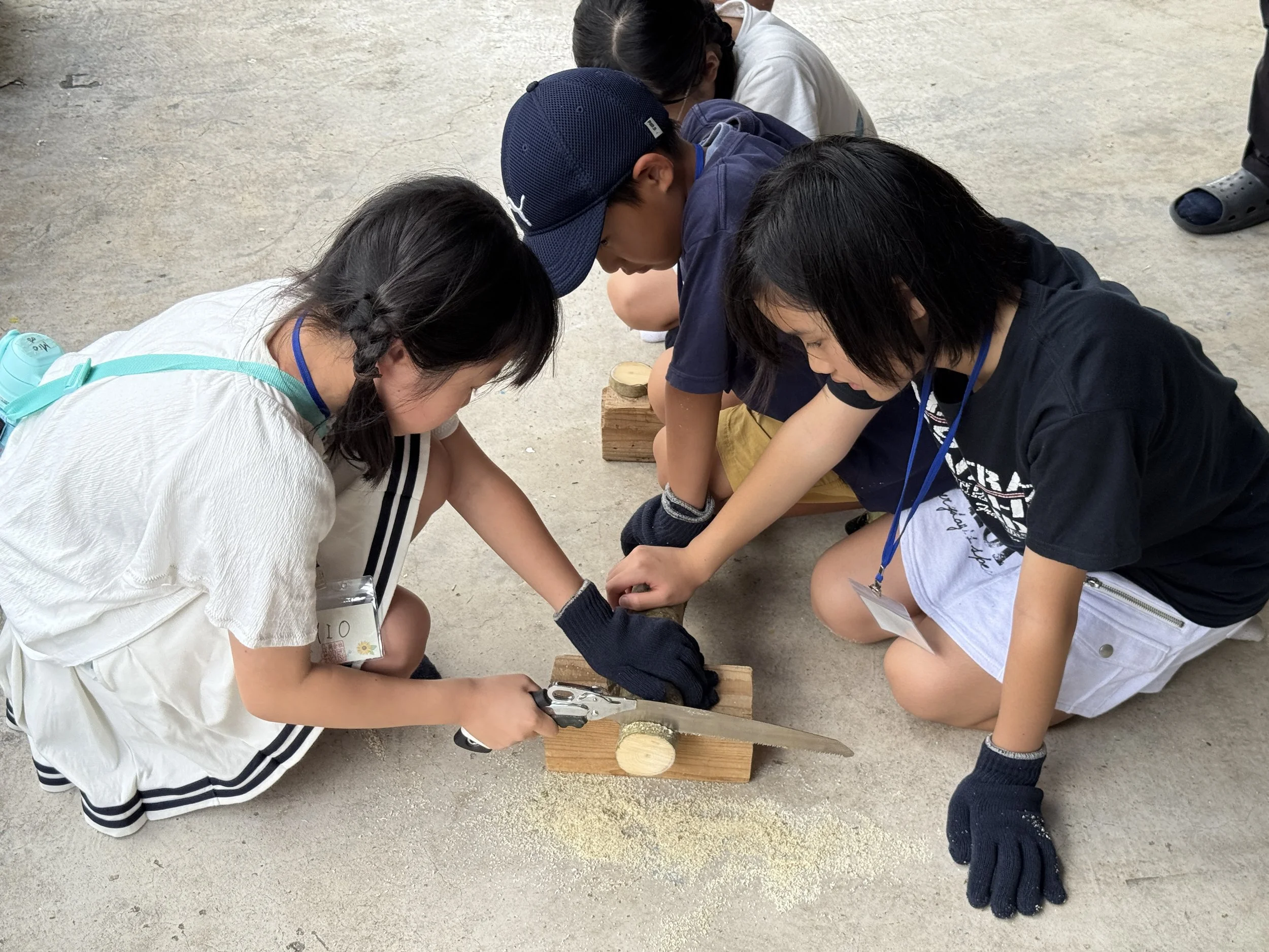 子供たちが木材をのこぎりで切る実践活動をしている