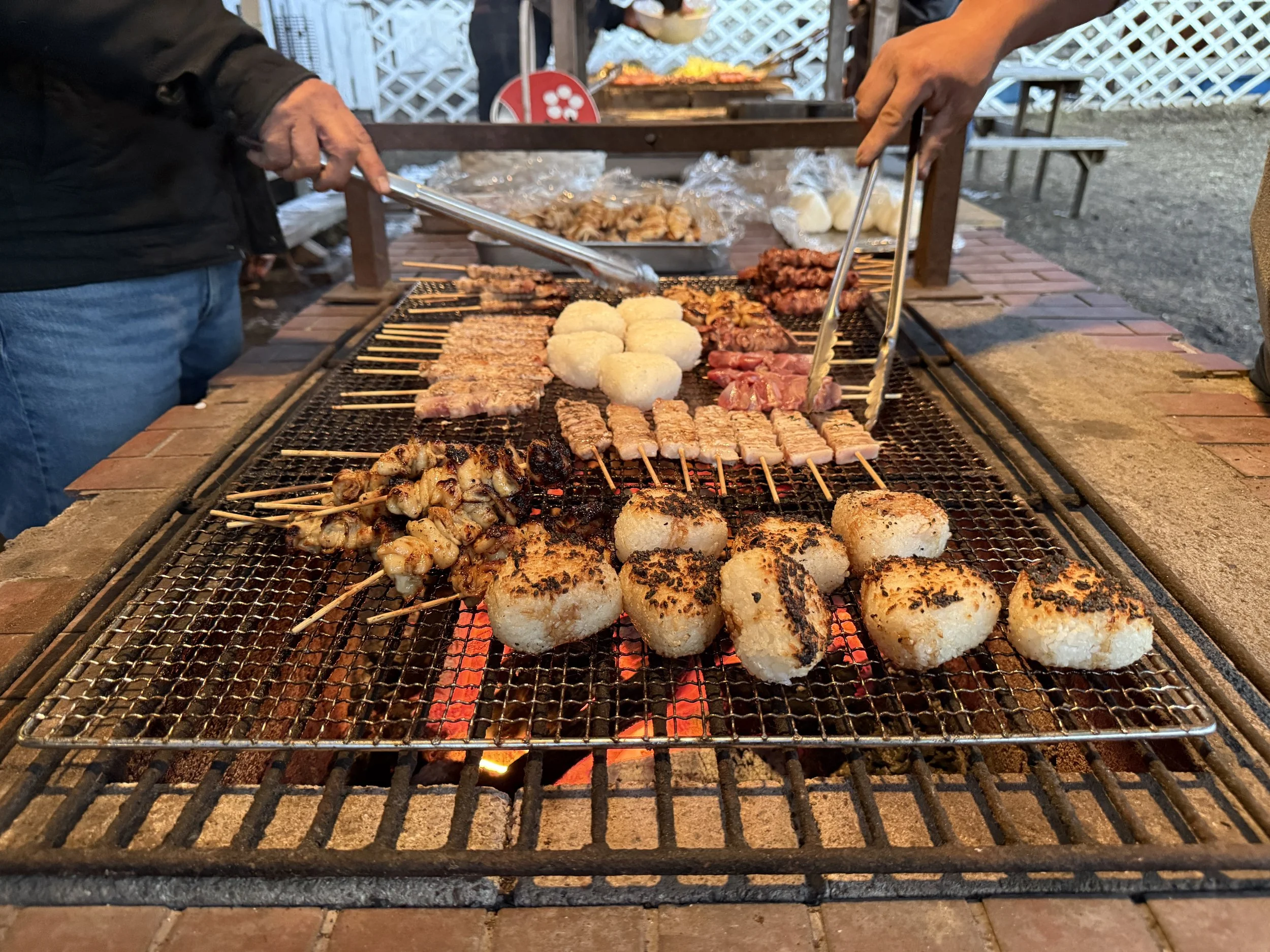 炭火で焼かれている串焼きの料理を屋外で楽しむ様子