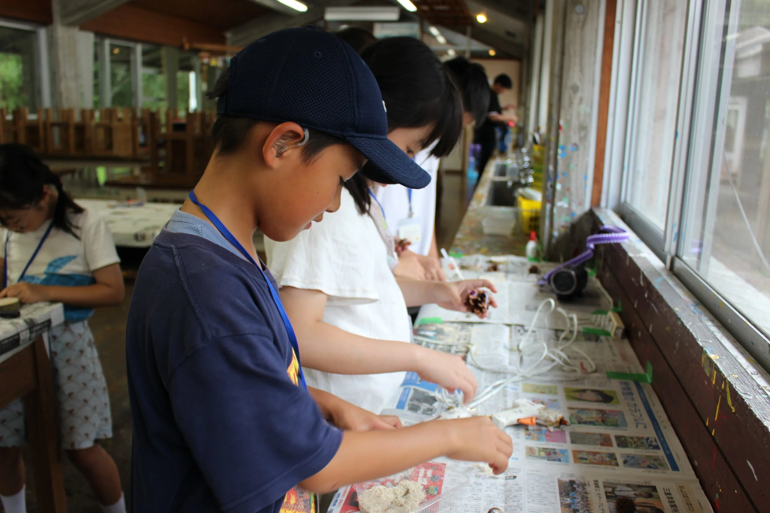 子供たちが新聞を敷いた作業台で工作をしている様子