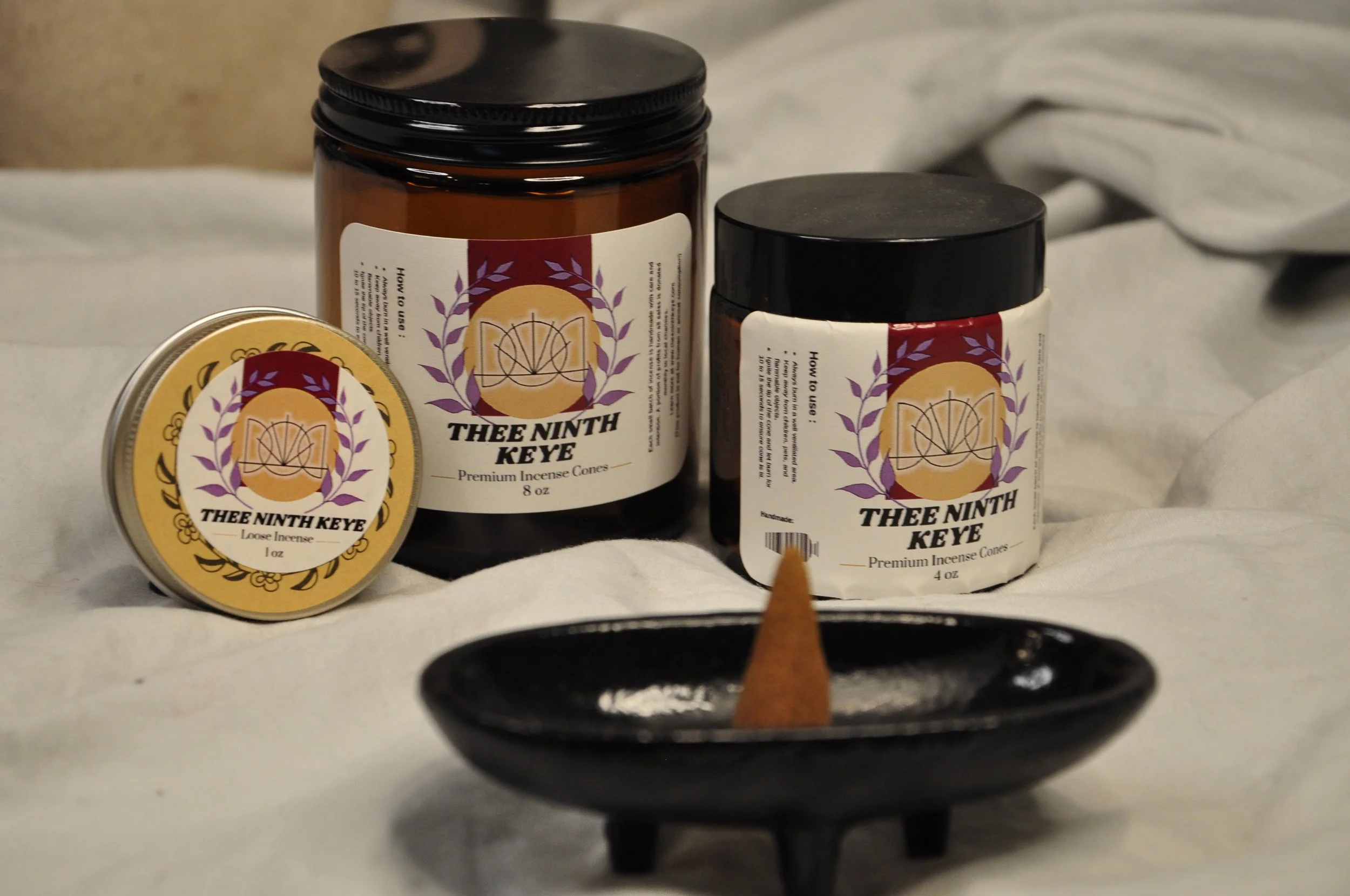 Three containers of Thee Ninth Keye premium incense cones, with the labels showing the brand logo and product description, placed on a black incense holder with a small holder in front.