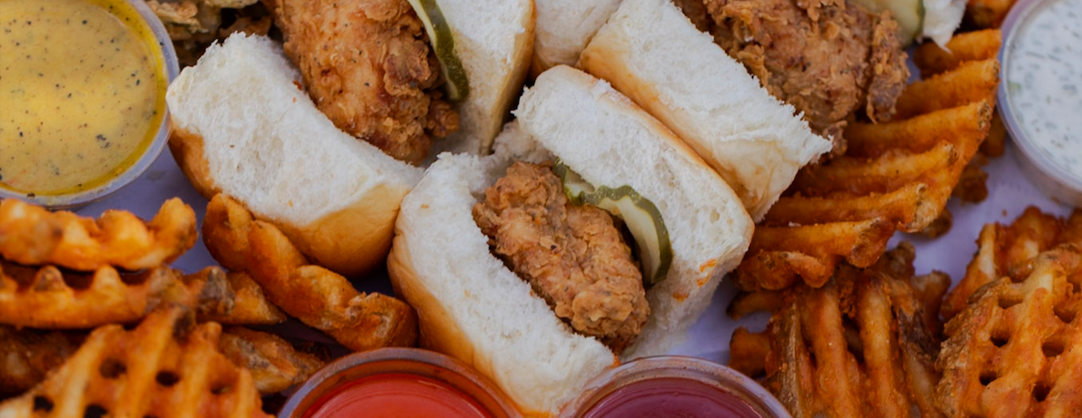 Cropped image of sliders, sauces, and waffle fries.