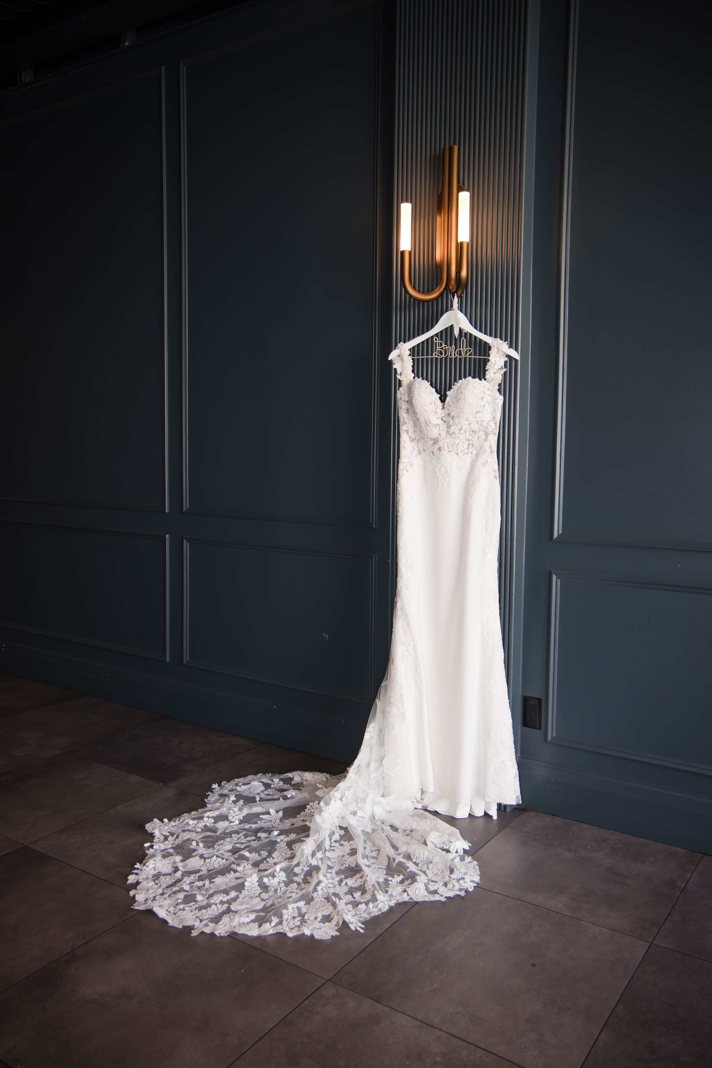 Elegant white wedding dress with lace details hanging on a hanger with a
