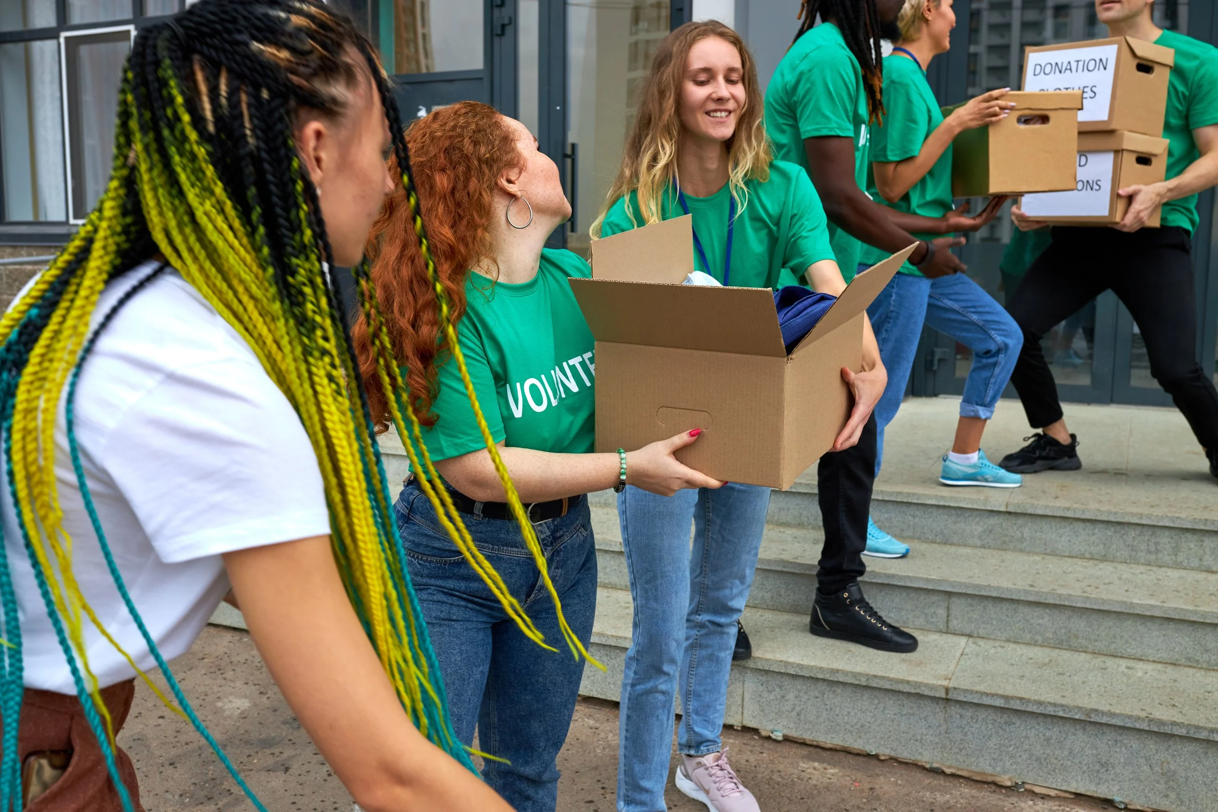 Group of volunteers carrying donation boxes outside building