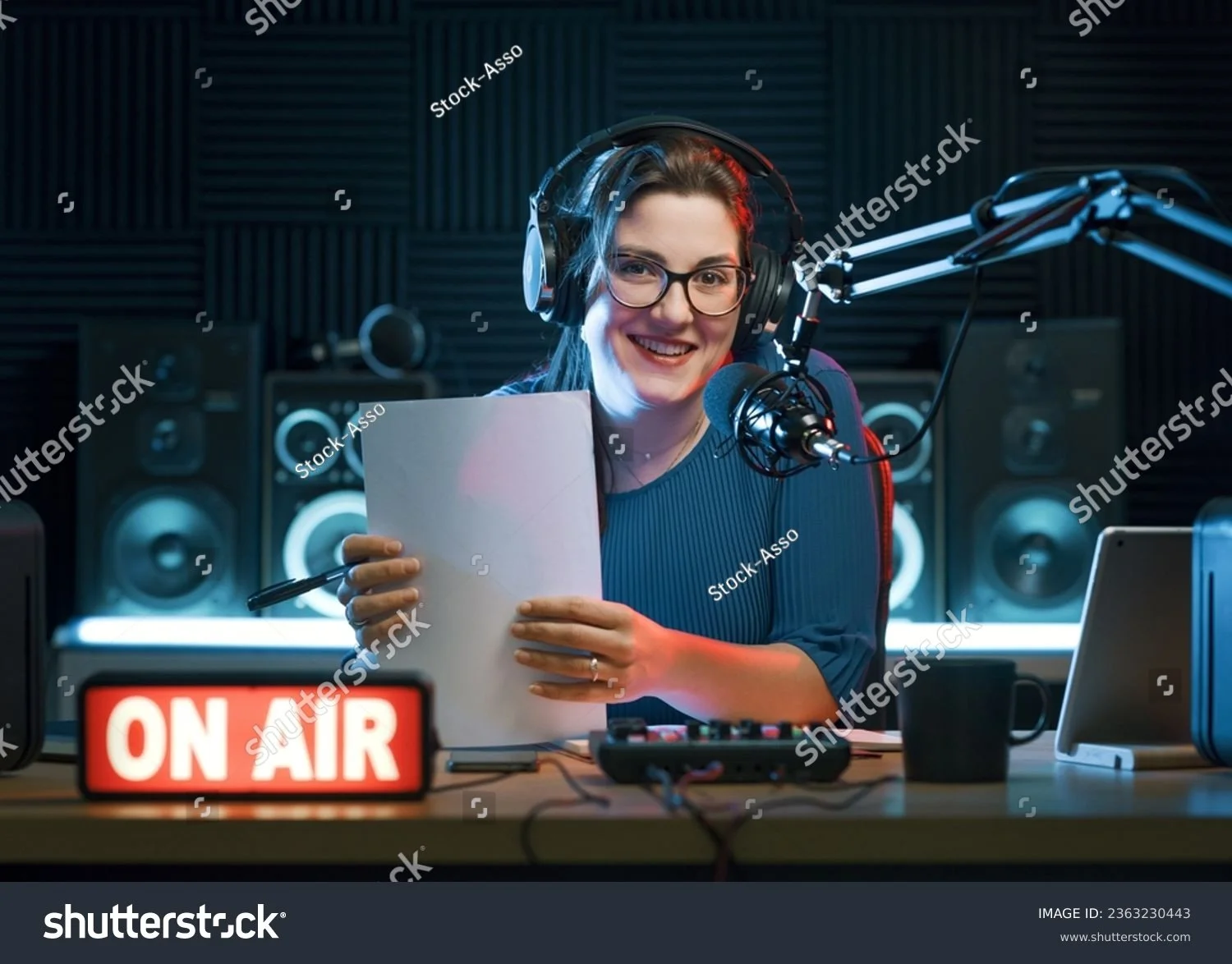 Radio DJ holding sheets of paper in a studio