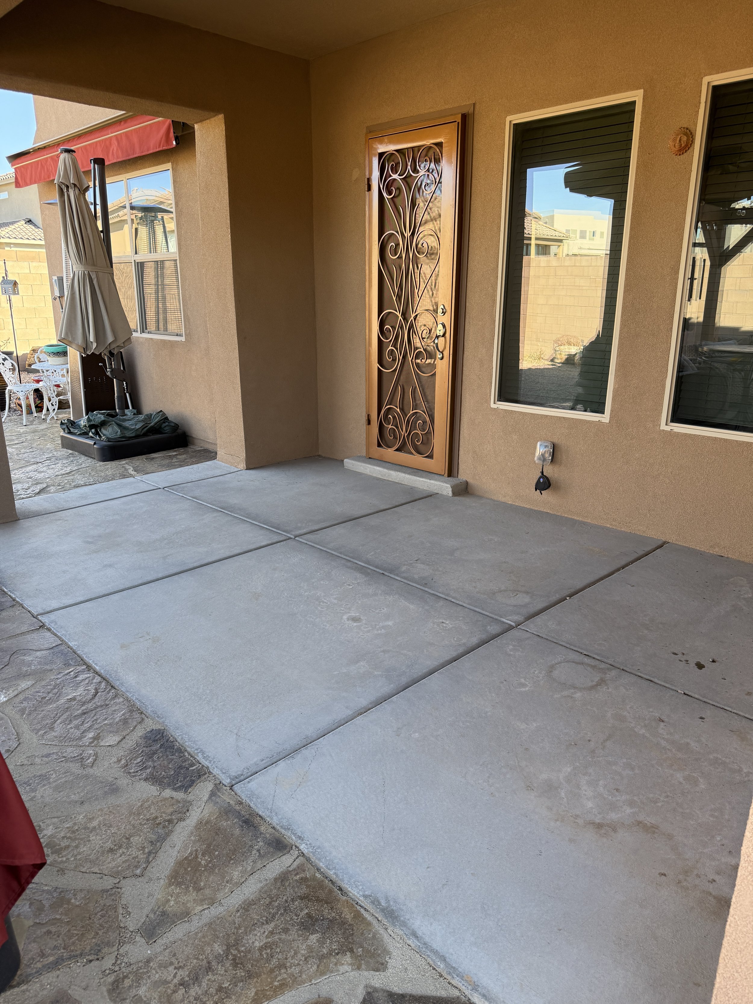 Patio with decorative door, two windows, and outdoor umbrella.