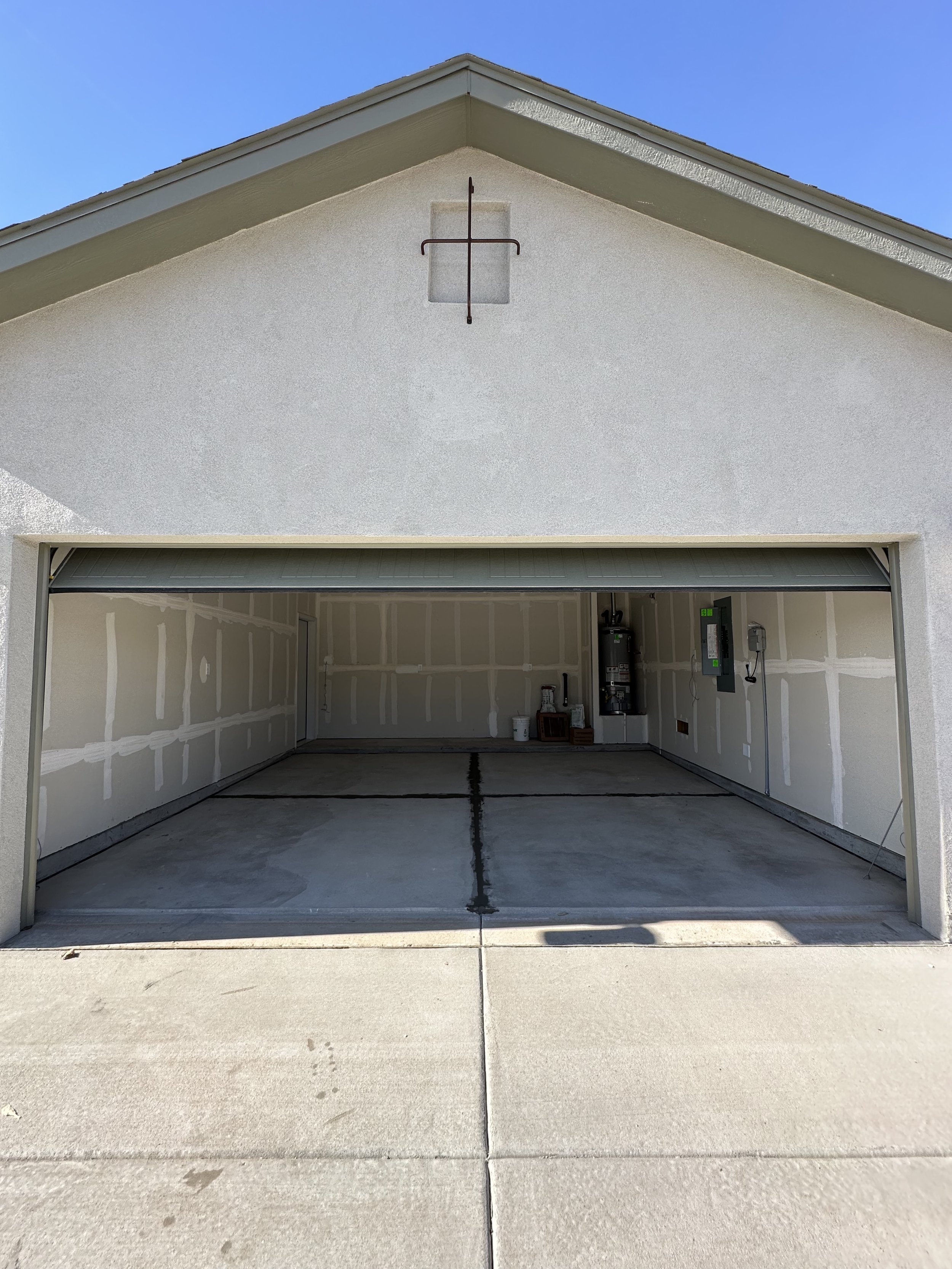 Open empty garage with drywall interior and concrete floor.