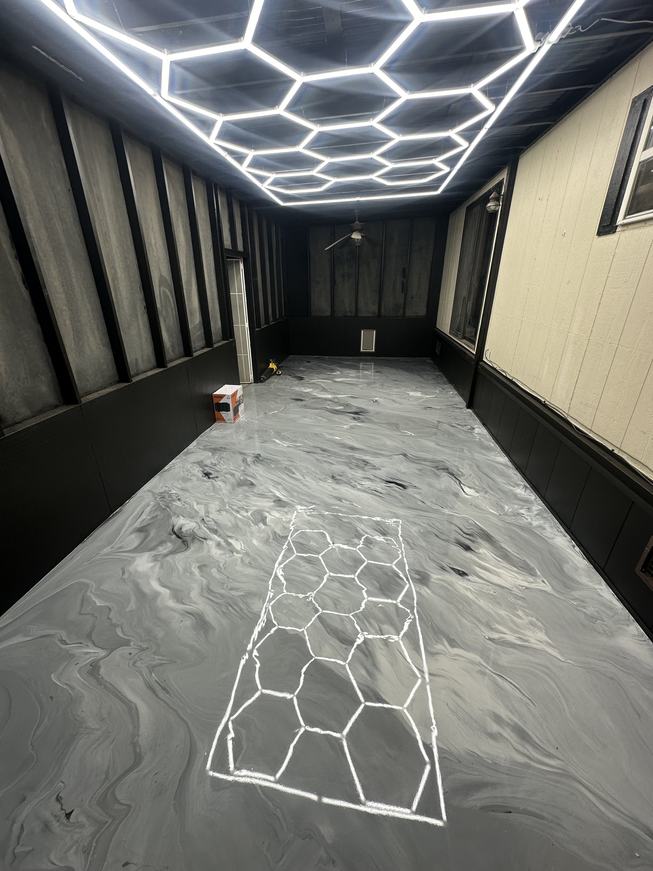 Room with hexagonal LED lights, gray marbled floor, and rectangular hexagon pattern on floor