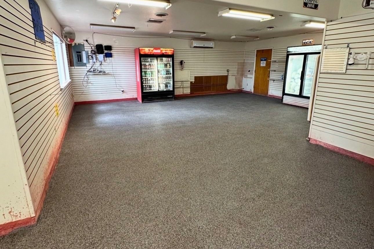 An empty room with slatwall panels, a carpeted floor, a beverage cooler, and an ice freezer.