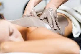 Person receiving a massage, lying face down with a massage therapist applying lotion or oil on their back.