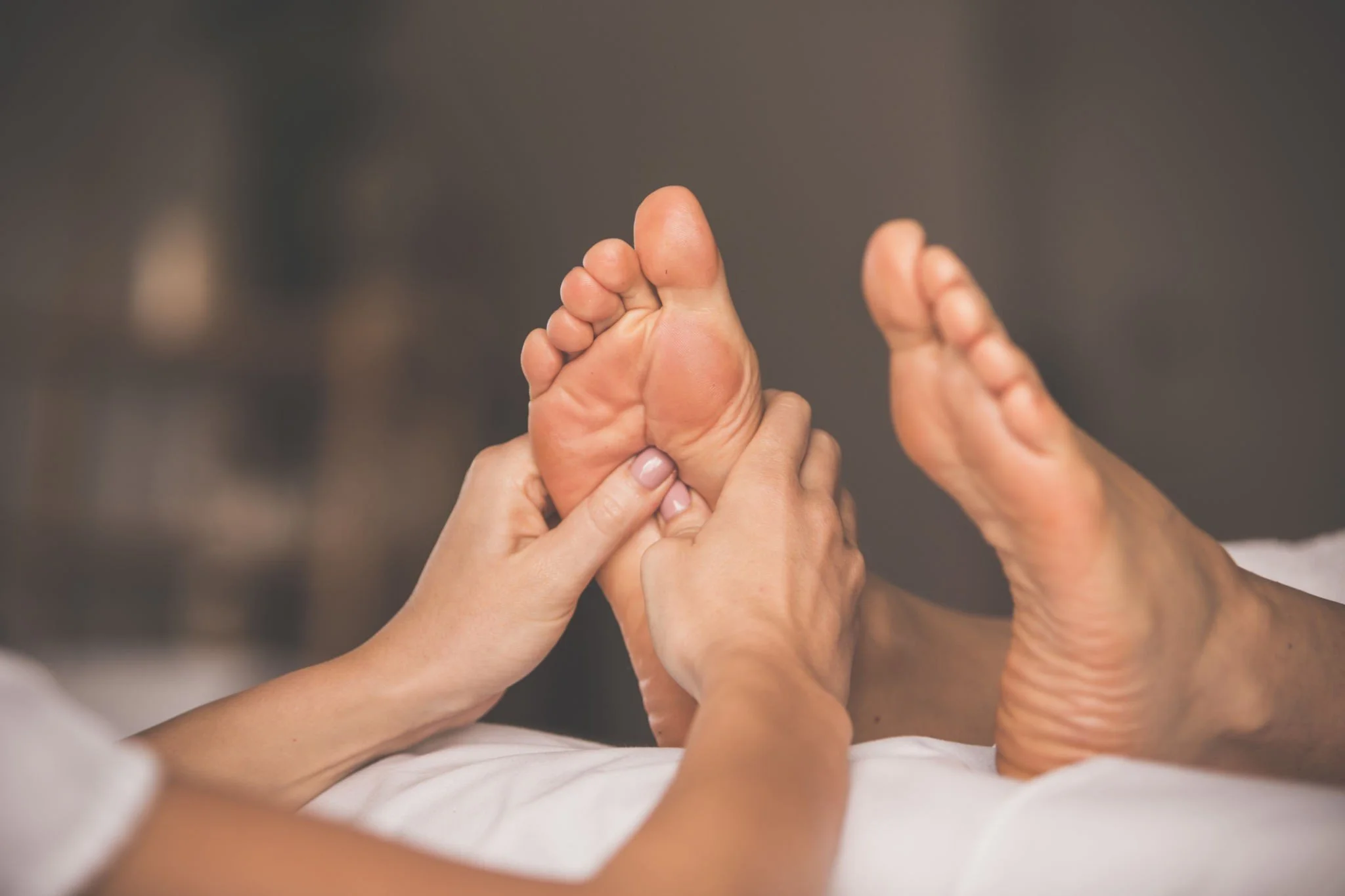 Hands giving a foot massage to a person's bare foot.