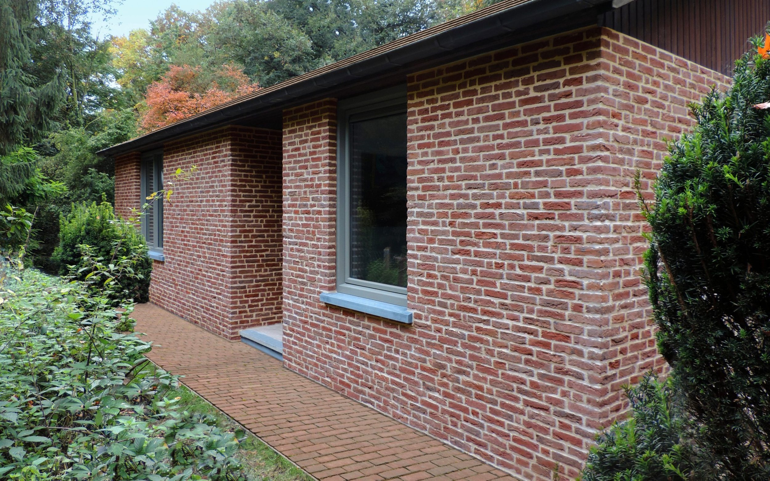 Bakstenen gebouw omringd door groene struiken en bomen.
