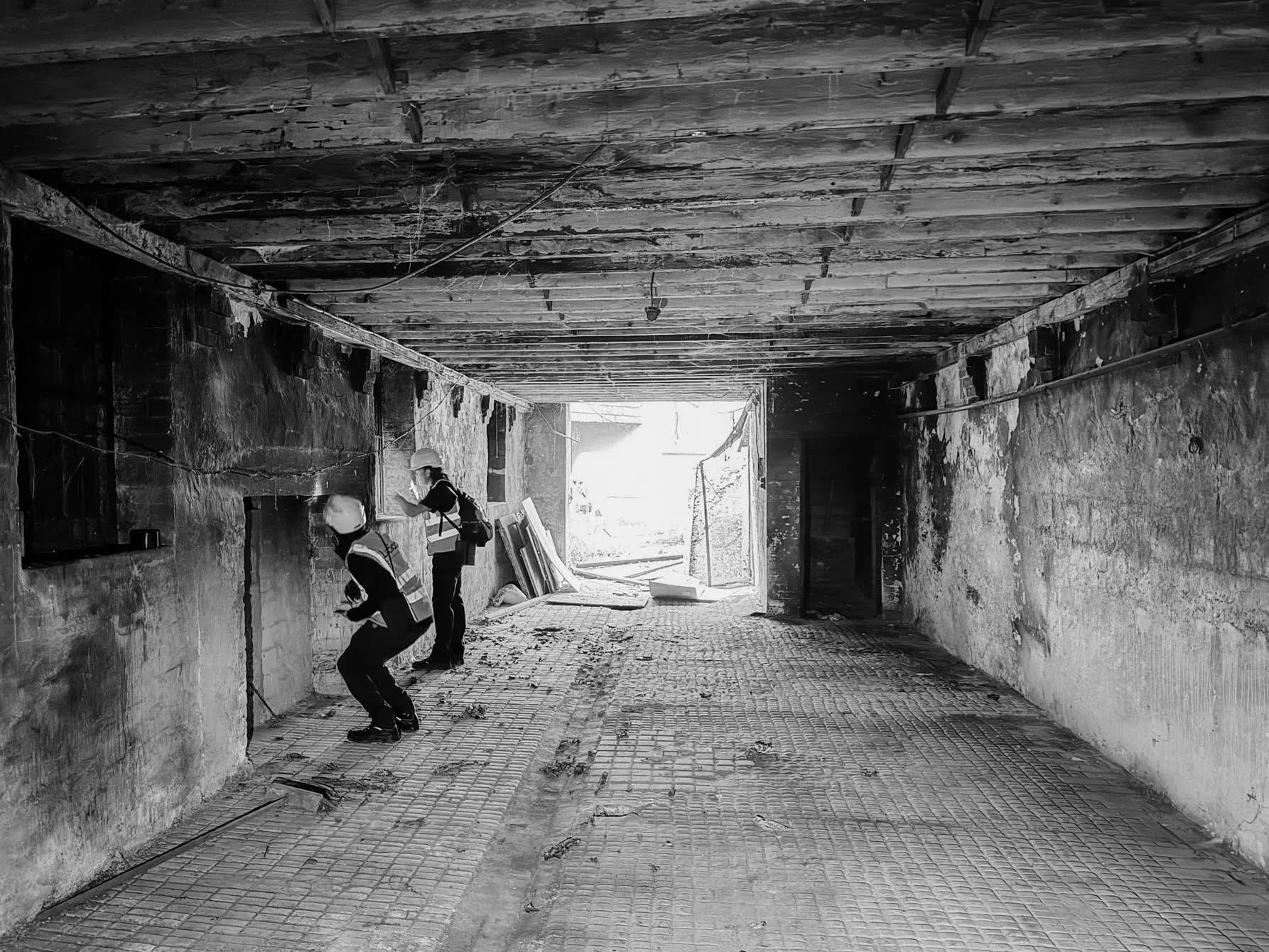 Two people in hi-viz and hard-hats inspecting a dangerous structure