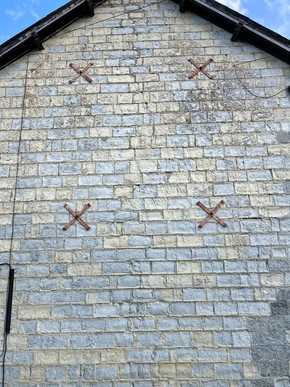 Exterior wall of listed Somerset Blue Lias stone farmhouse showing decay at inspection